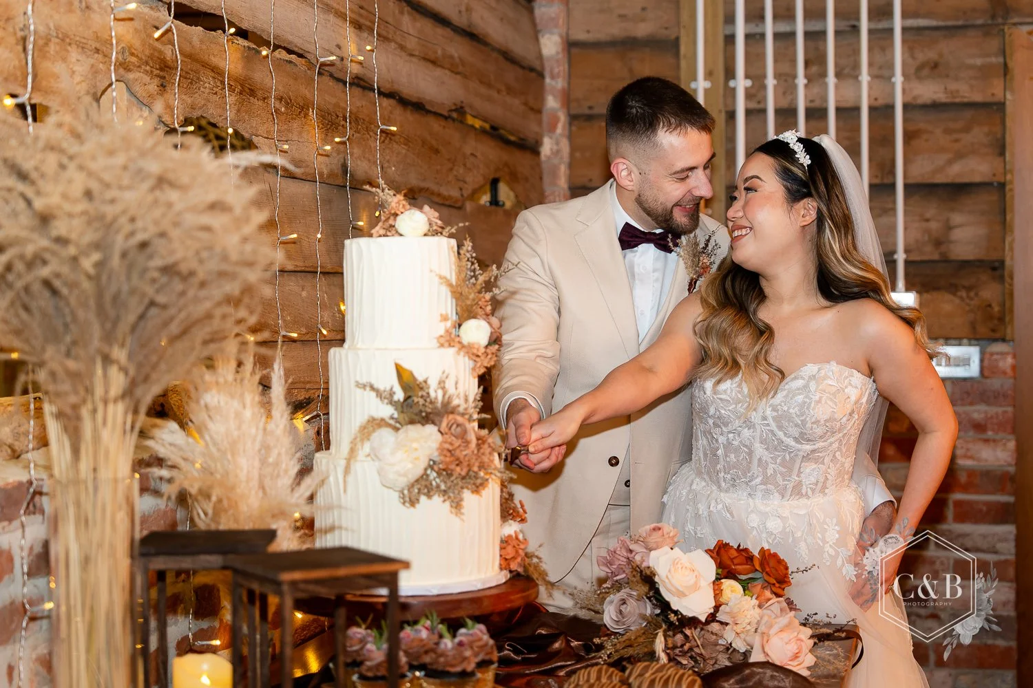 A Bride and Groom cut a cake during a styled shoot at Wellinton Barn