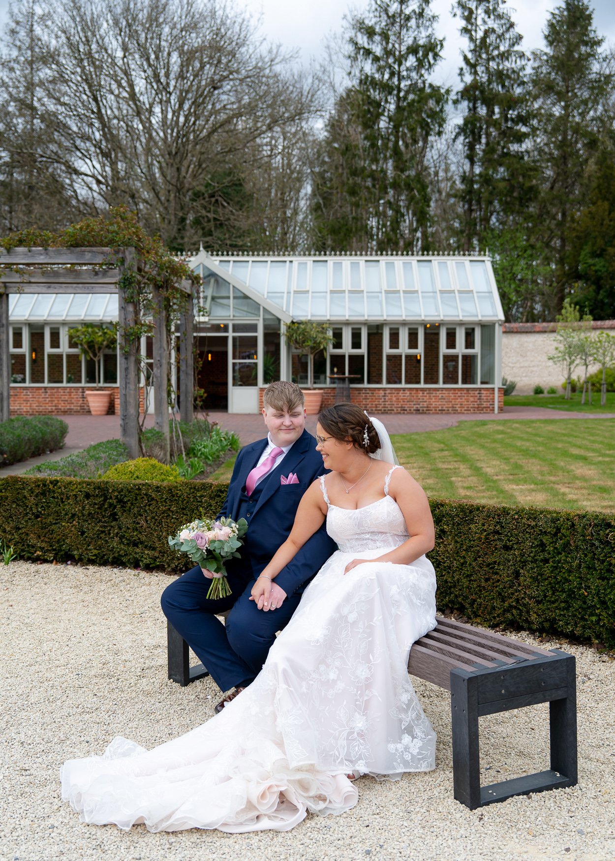 A Bride and Groom sit in the walled garden of Syrencot smiling at each other
