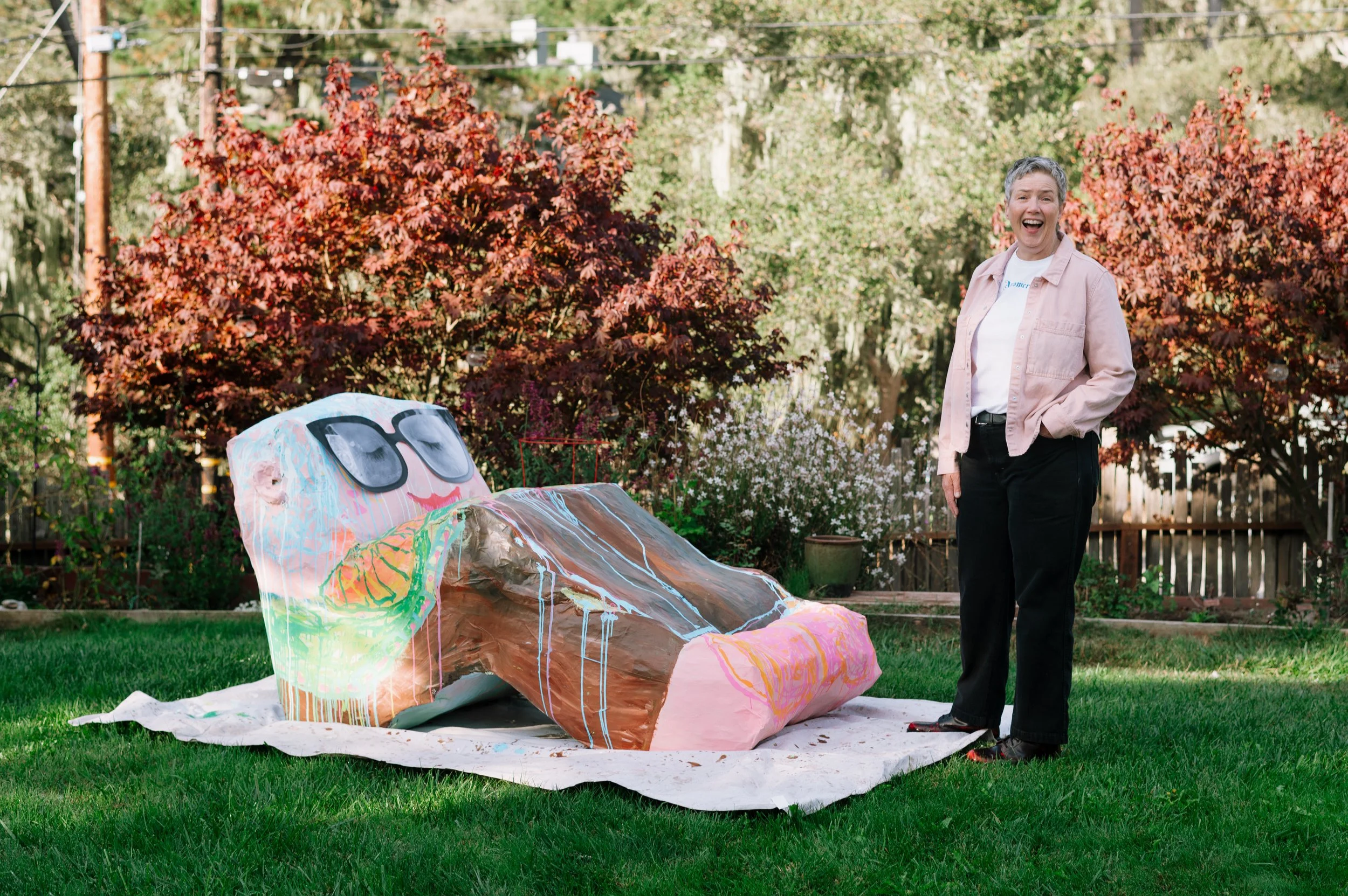 life sized paper máche sculpture of an artist as a recliner. Artist standing next to sculpture