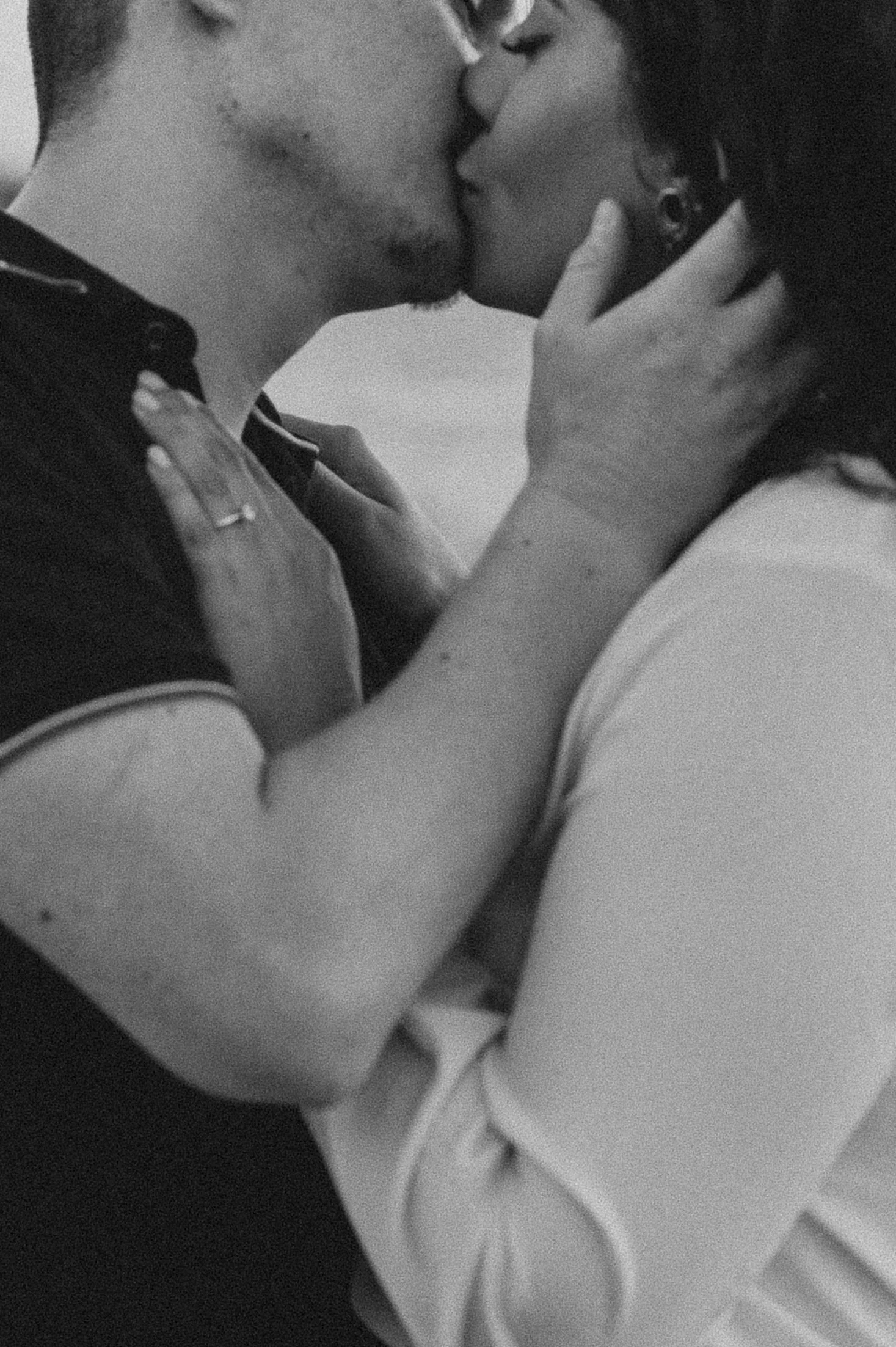 A black-and-white photo of a couple kissing, with the woman holding the man's face and the man holding her shoulder.