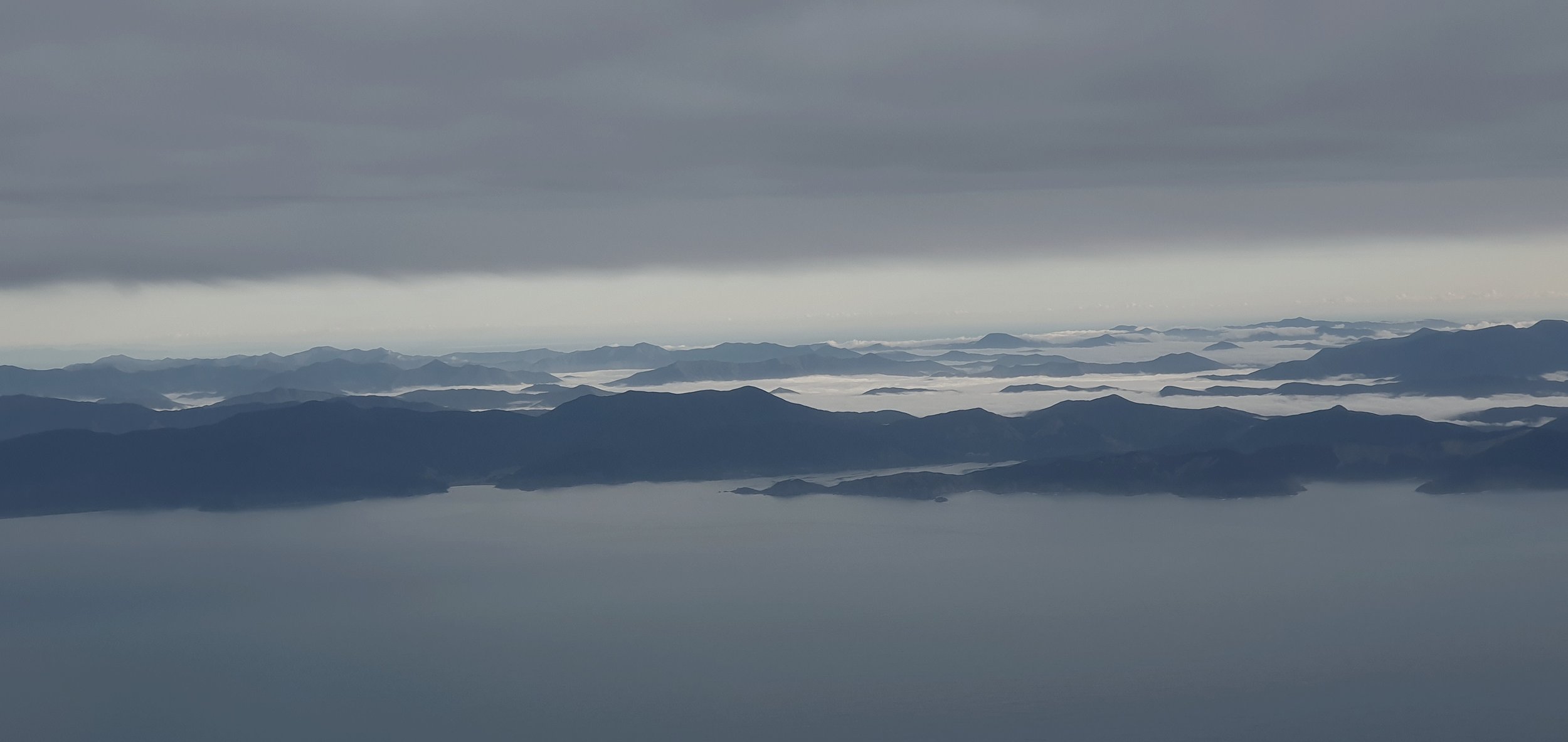 Layered mountain ridges emerging through low cloud