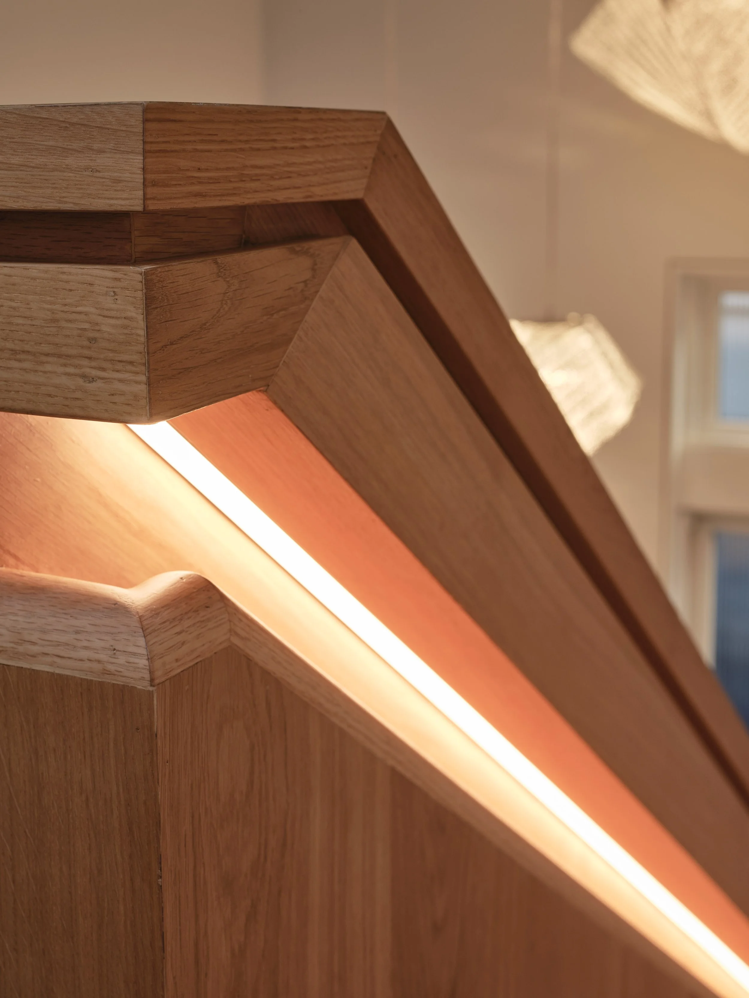 Sculptural wood staircase with custom underlit handrail 