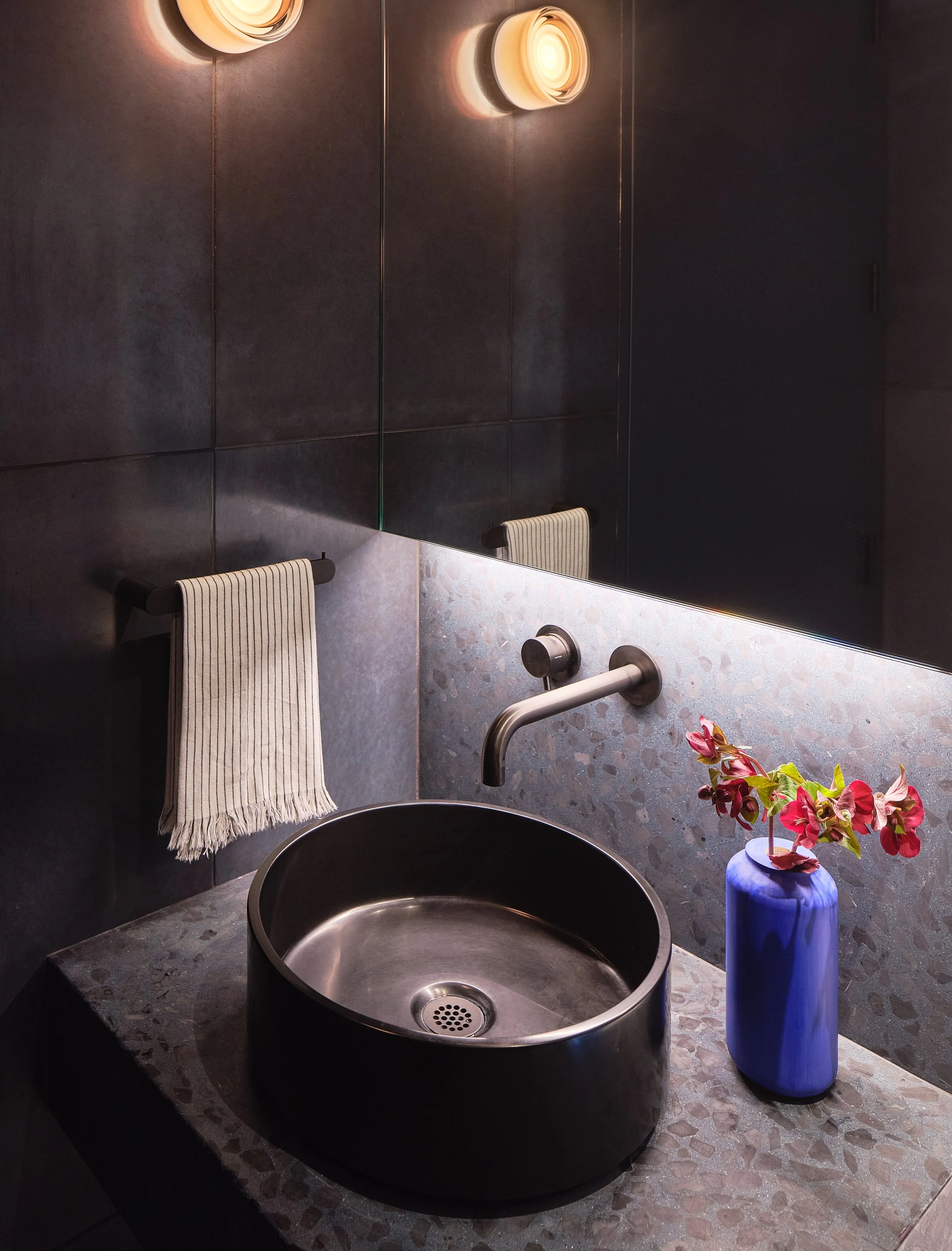 Moody powder room with stone and sculptural lighting