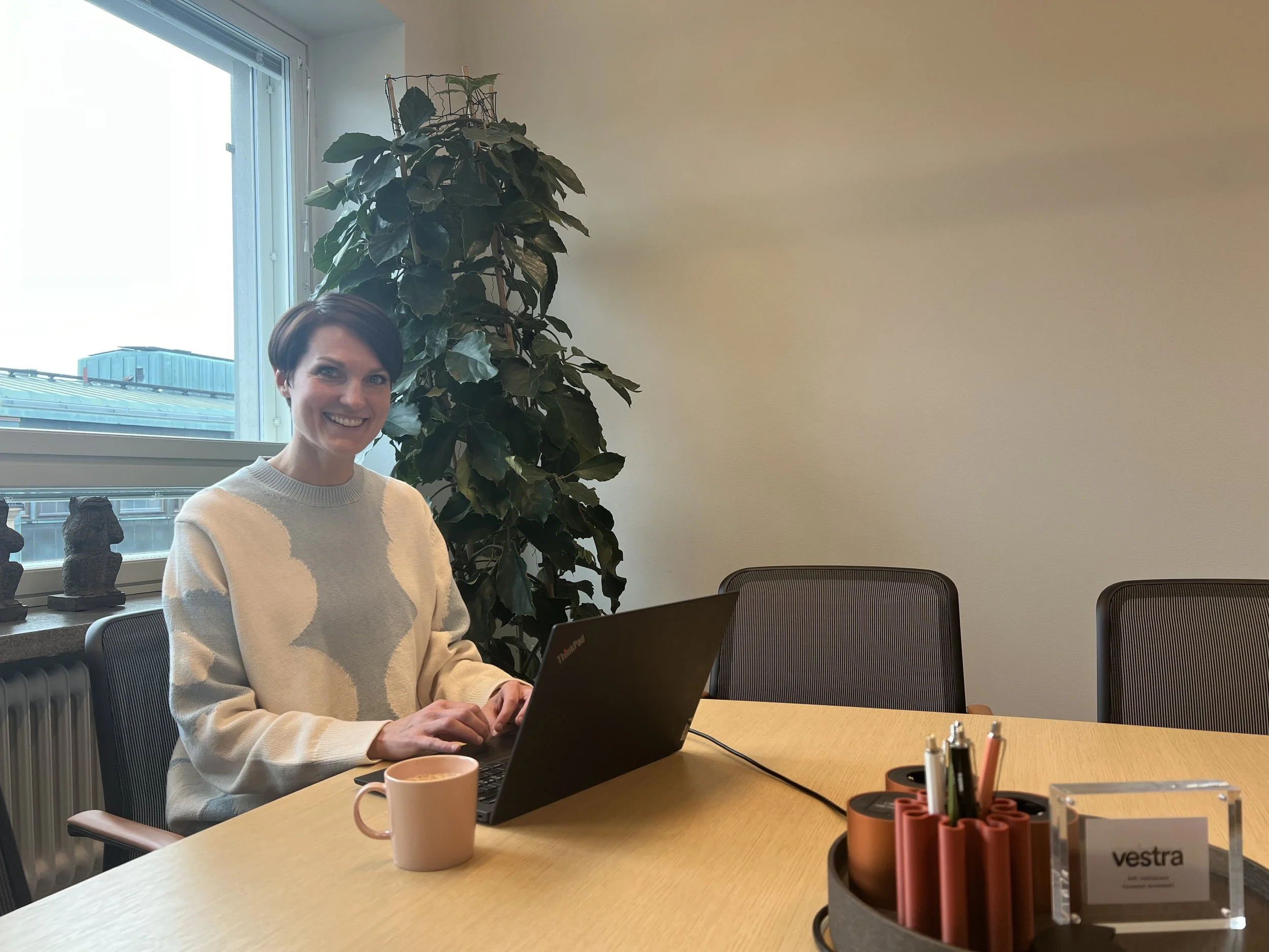 Annika istumassa pöydän äärellä tietokoneella.