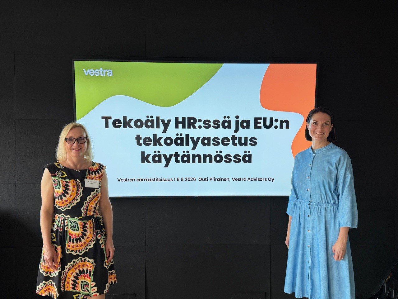 Kaksi asiantuntijaa katsoo kameraan näytön edessä, jossa lukee "Tekoäly HR:ssä ja EU:n tekoälyasetus käytännössä". Katso vinkit tekoälyn vastuulliseen käyttöön!