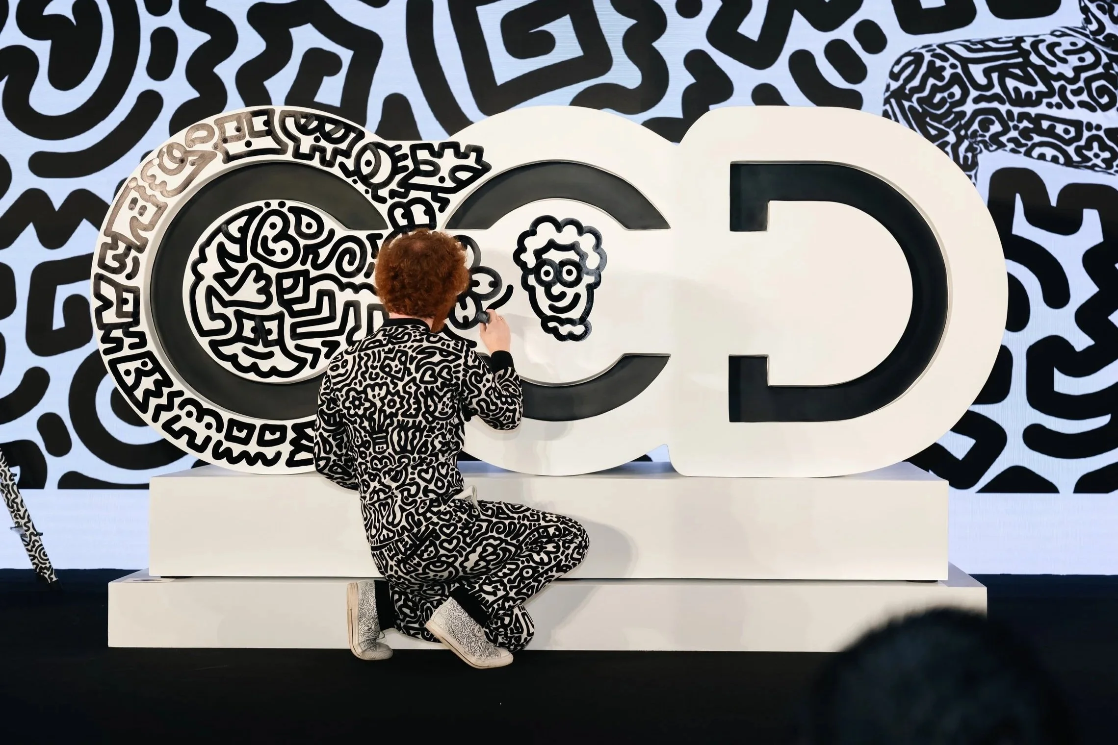 Mr Doodle interacting directly with a large-scale mural, blurring the boundary between artist, artwork, and City of Dream.