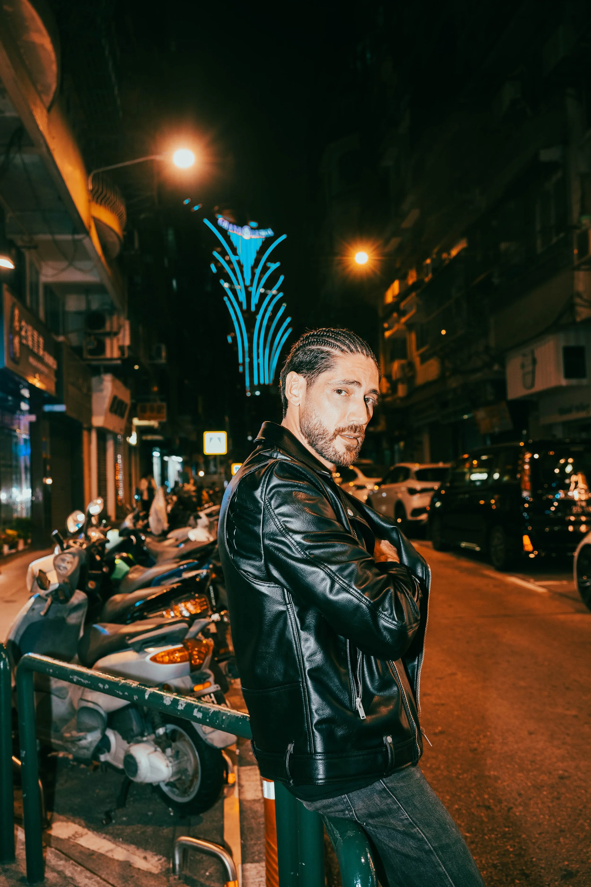 Cinematic night portrait of Angelo Rodrigues in Macau, featuring light trails, traffic motion, and the illuminated Grand Lisboa skyline. Retrato noturno cinematográfico de Angelo Rodrigues em Macau, com rastos de luz, movimento urbano e o skyline ilu