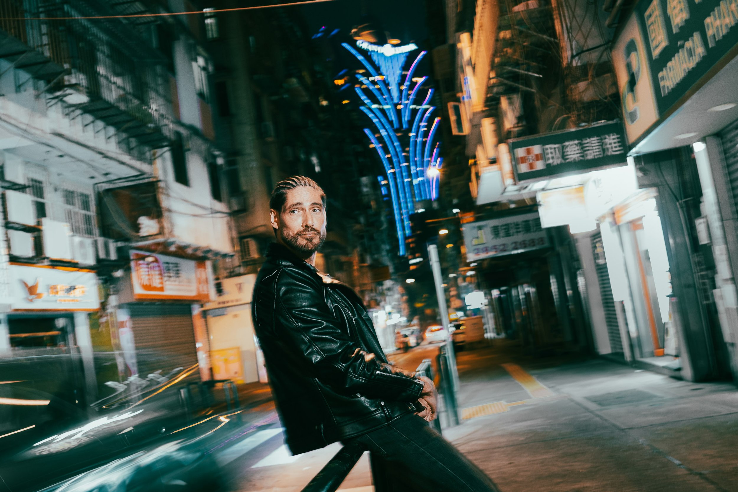 Photographed around Grand Lisboa, these portraits place Angelo Rodrigues within the pulse of modern Macau. Surrounded by neon lights, traffic, and architectural contrasts, the images capture the city in motion—where glamour, density, and urban rhythm
