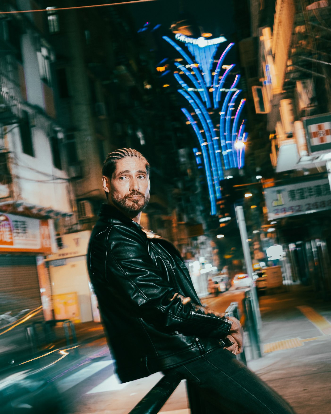 Street portrait of Angelo Rodrigues in central Macau, combining night photography, motion blur, and Grand Lisboa casino architecture. Retrato de rua de Angelo Rodrigues no centro de Macau, combinando fotografia noturna, desfoque de movimento e a arqu