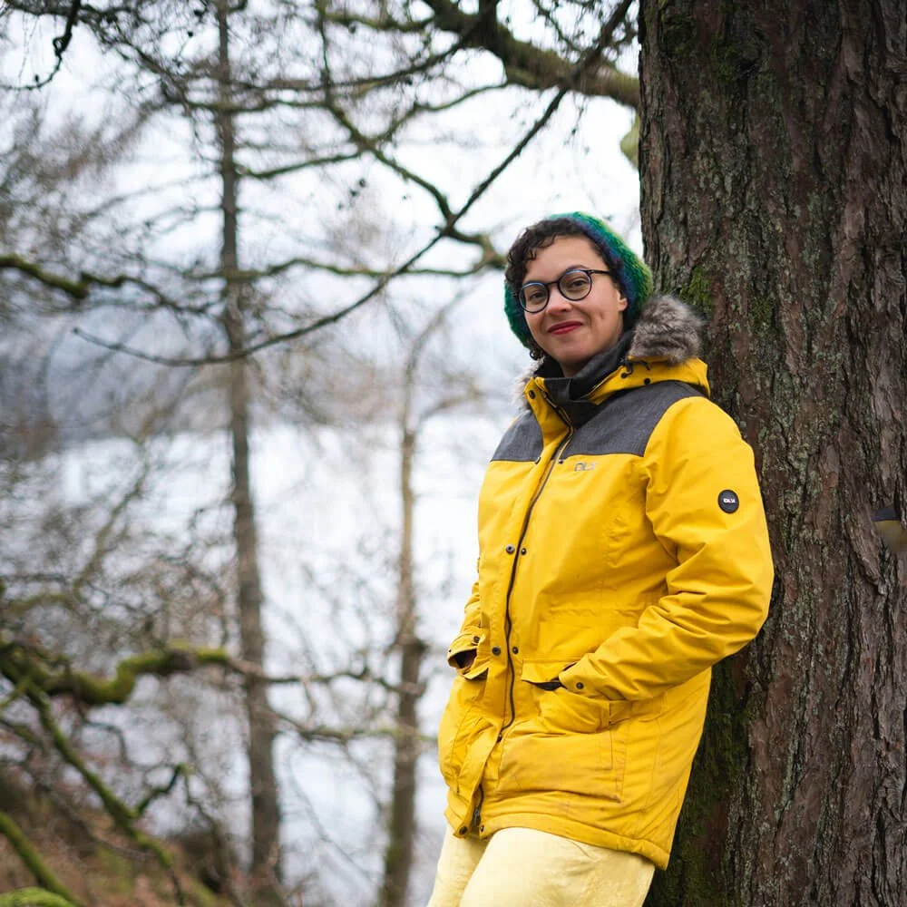Composer Ella Jarman-Pinto leaning on a tree by the lake2.jpg