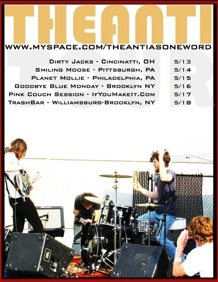 A band of young musicians performing outdoors on a stage, with a poster behind them listing tour dates and locations.