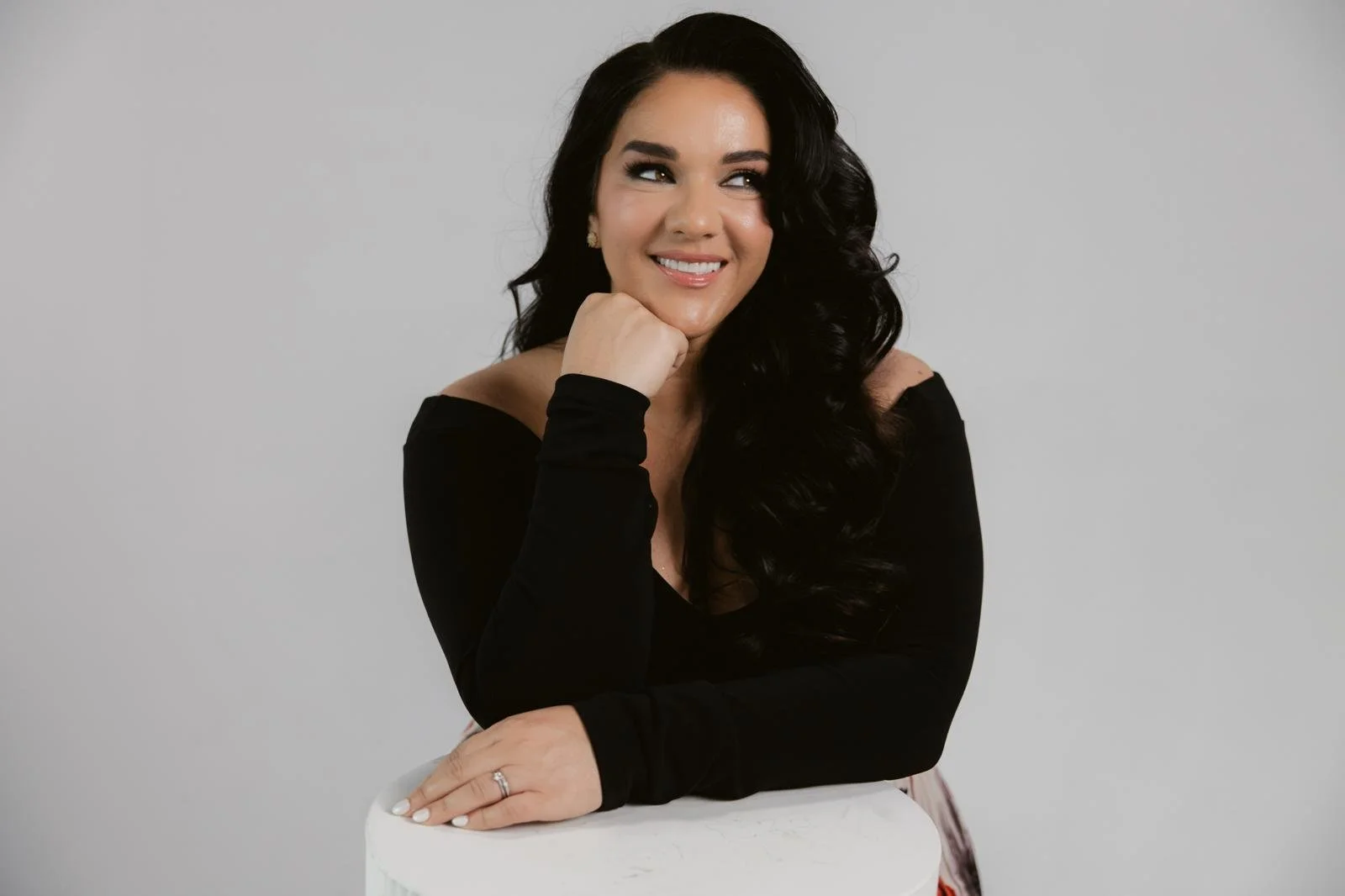 Smiling portrait of Jeanette Vecchione-Donatti leaning on a white pedestal