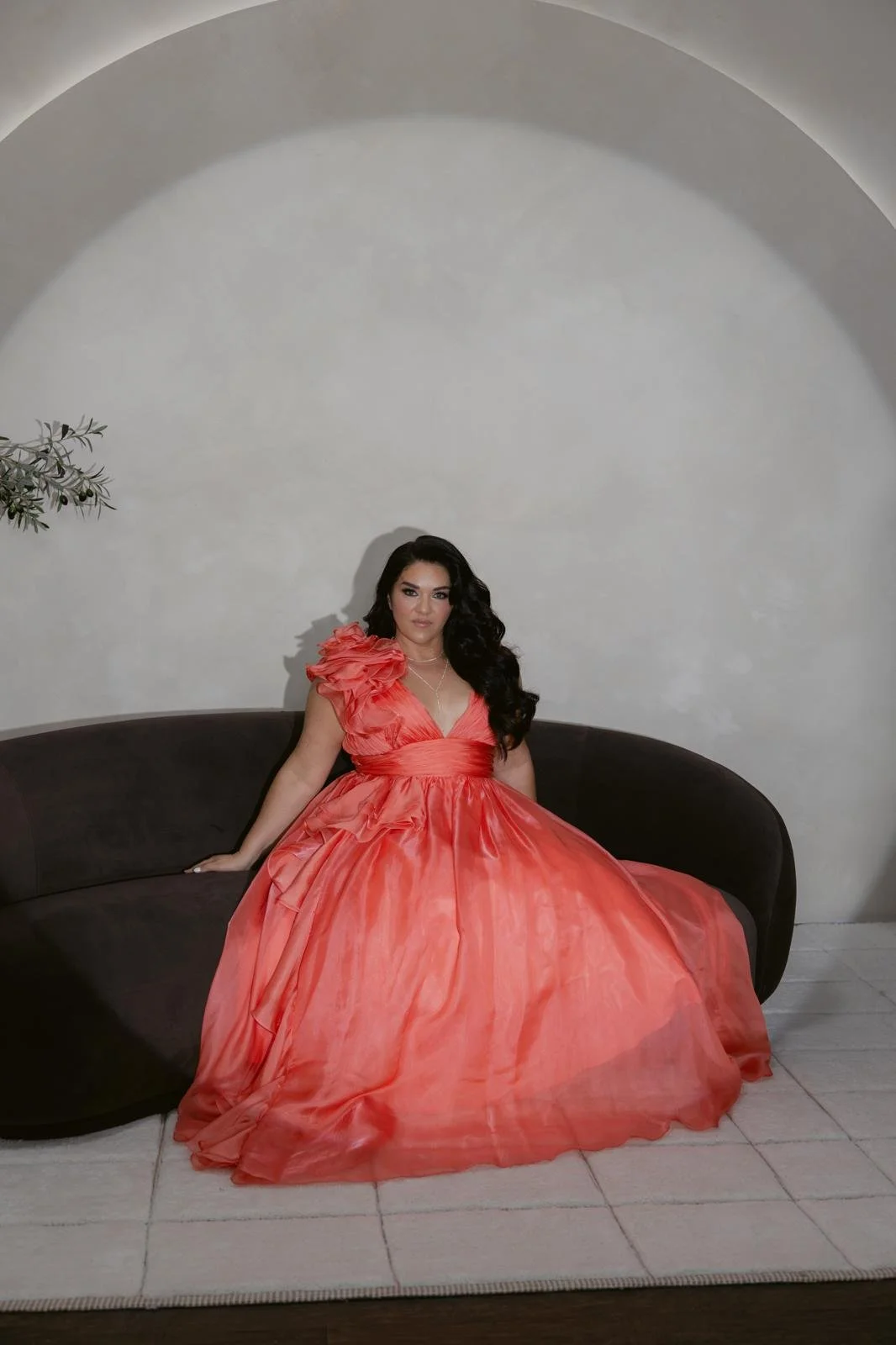 Jeanette Vecchione-Donatti in a coral organza gown on a curved sofa