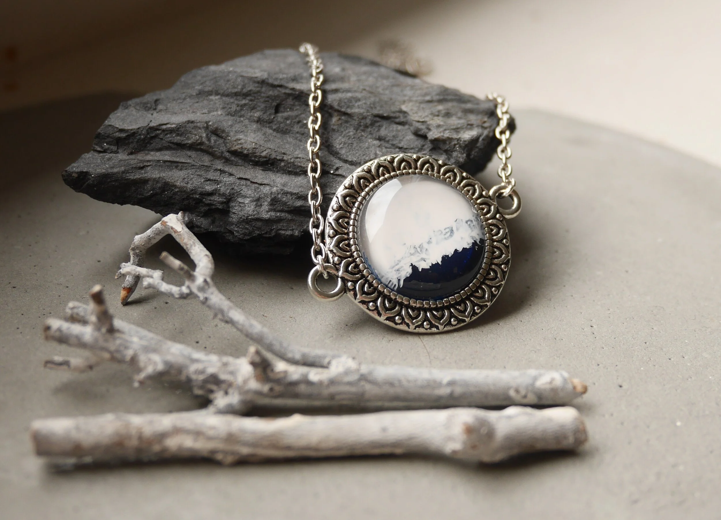 Silberne Halskette mit rundem, handbemaltem Glascabochon, dunkelblau und weiß, in verzierter Fassung