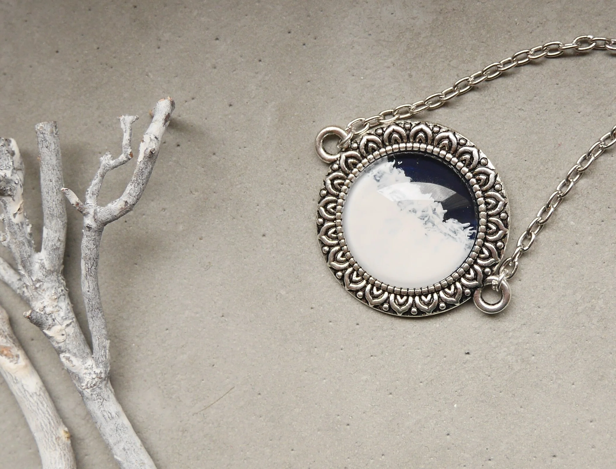 Silberne Halskette mit rundem, handbemaltem Glascabochon, dunkelblau und weiß, in verzierter Fassung