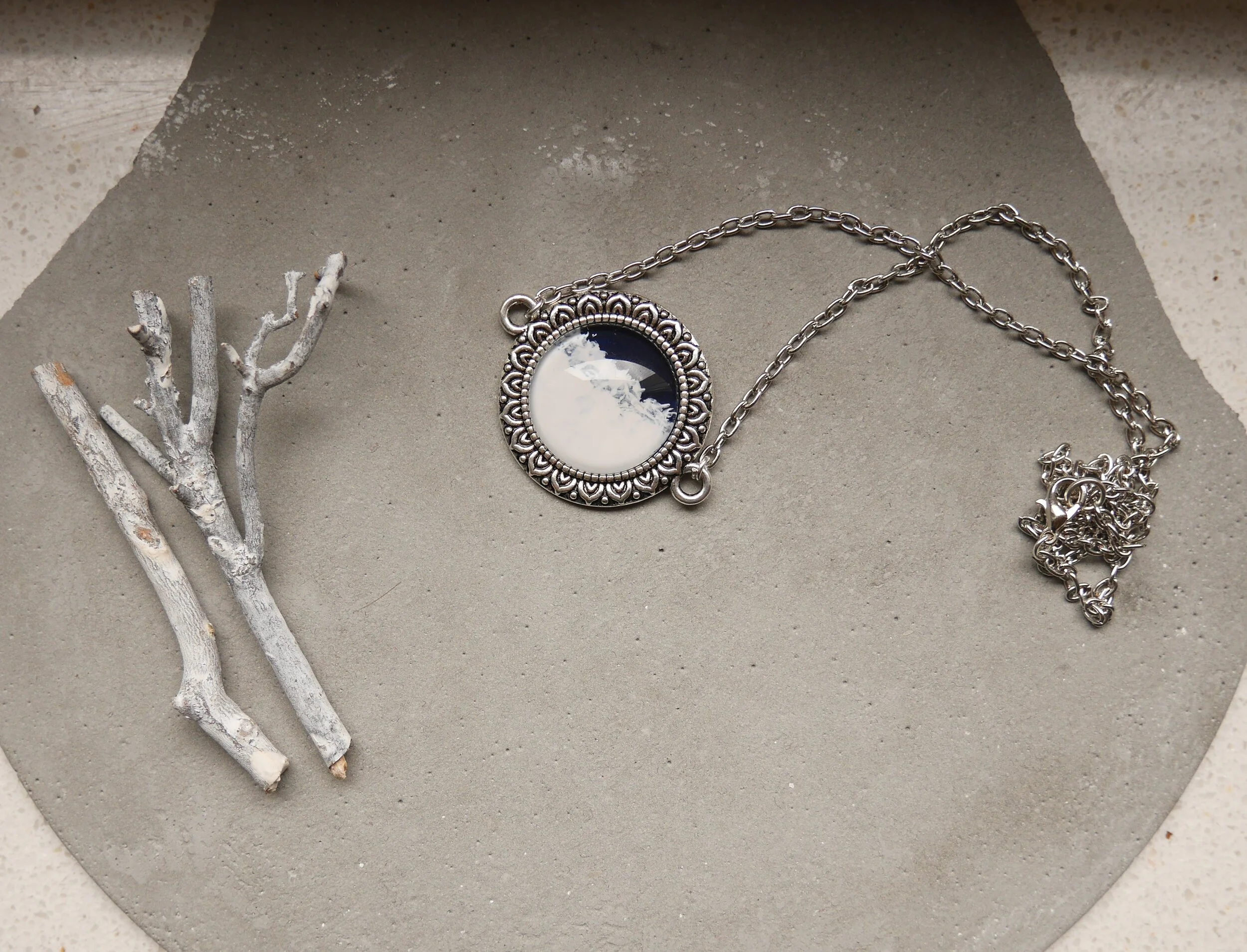 Silberne Halskette mit rundem, handbemaltem Glascabochon, dunkelblau und weiß, in verzierter Fassung