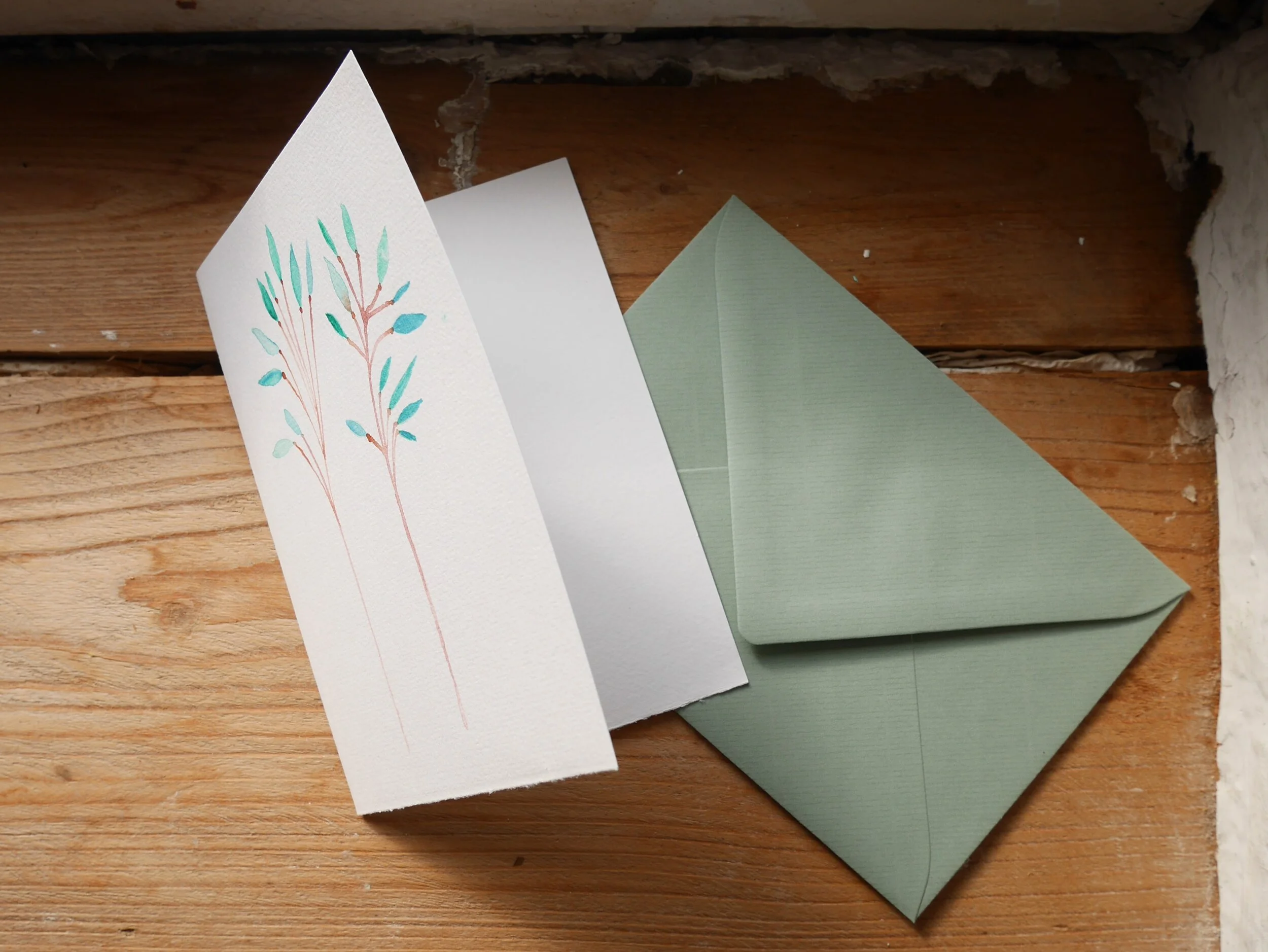 Klappkarte aus Papier mit Aquarellzeichnung und mildgrünem Umschlag Zwei zarte braune Zweige mit Pastellgrünen Blättern