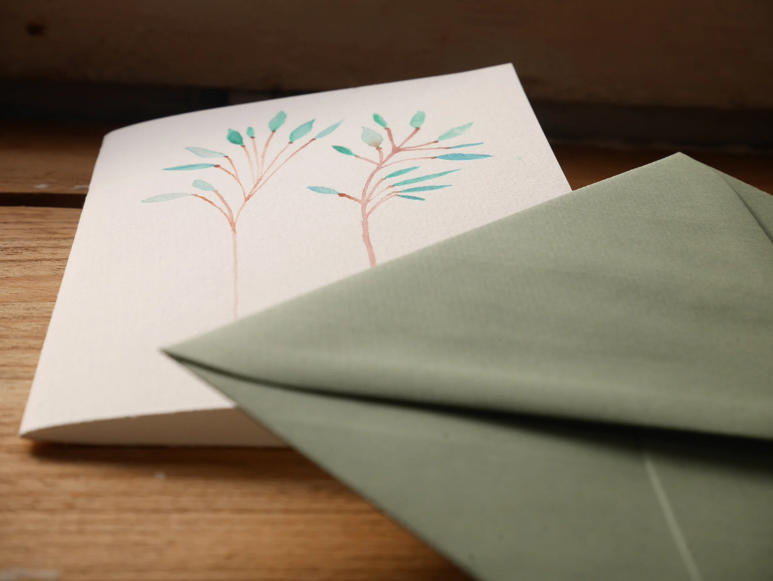 Klappkarte aus Papier mit Aquarellzeichnung und mildgrünem Umschlag Zwei zarte braune Zweige mit Pastellgrünen Blättern