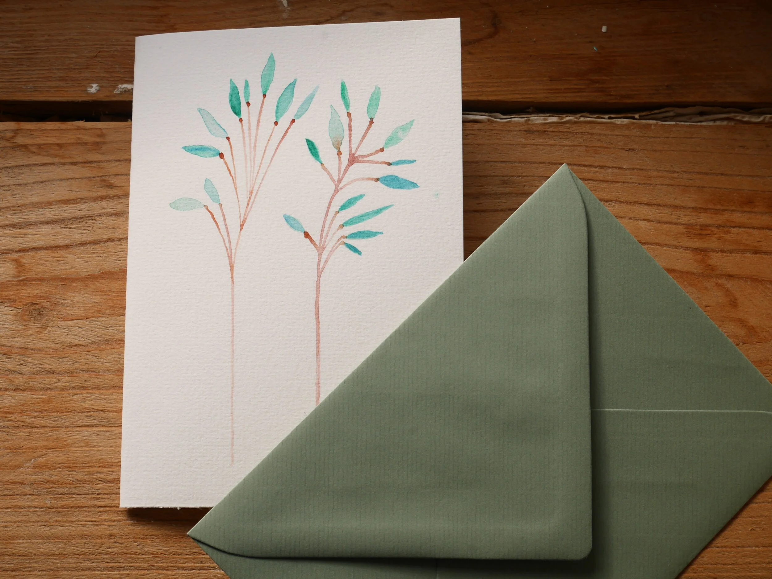 Klappkarte aus Papier mit Aquarellzeichnung und mildgrünem Umschlag Zwei zarte braune Zweige mit Pastellgrünen Blättern