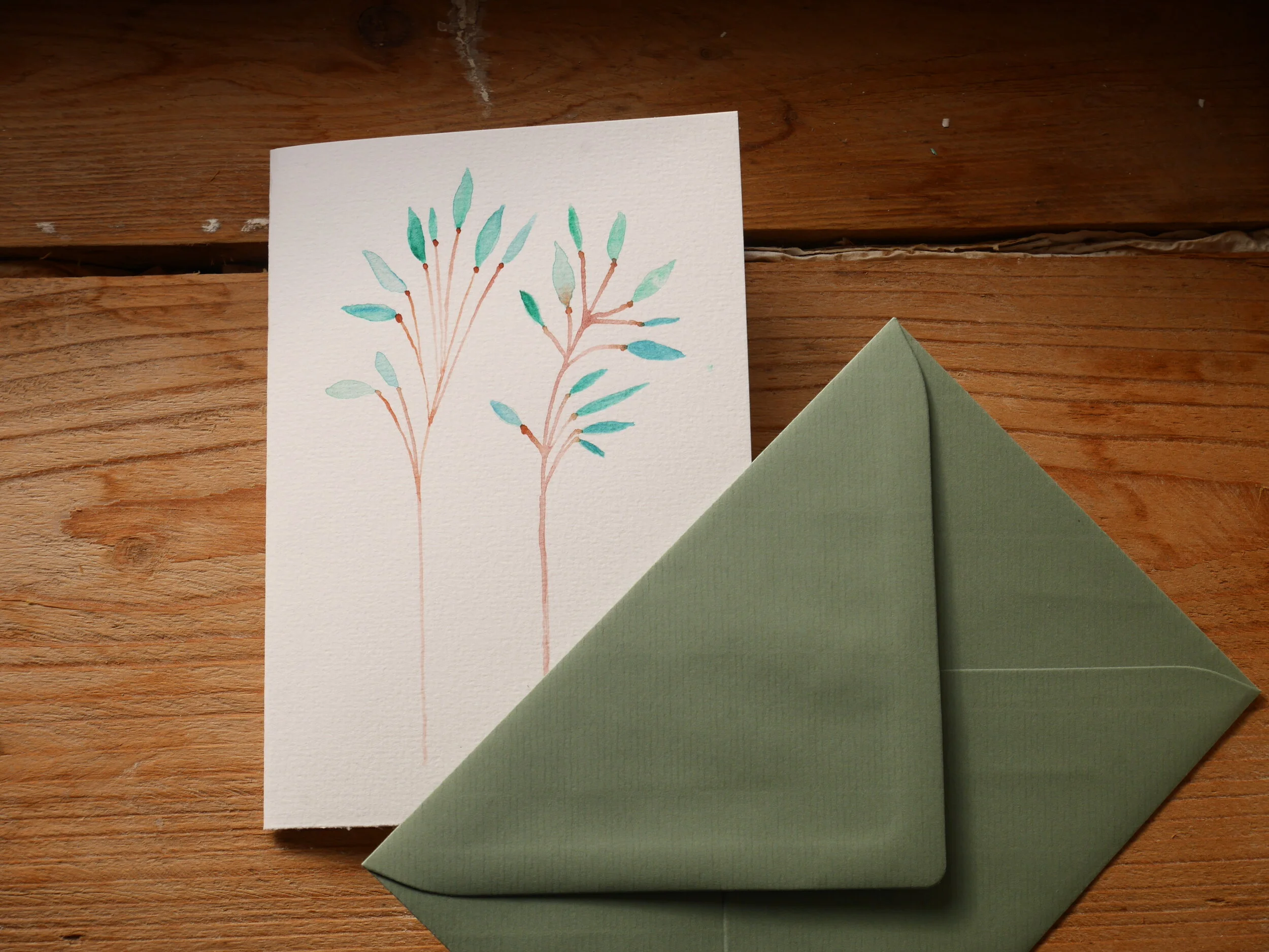 Klappkarte aus Papier mit Aquarellzeichnung und mildgrünem Umschlag Zwei zarte braune Zweige mit Pastellgrünen Blättern