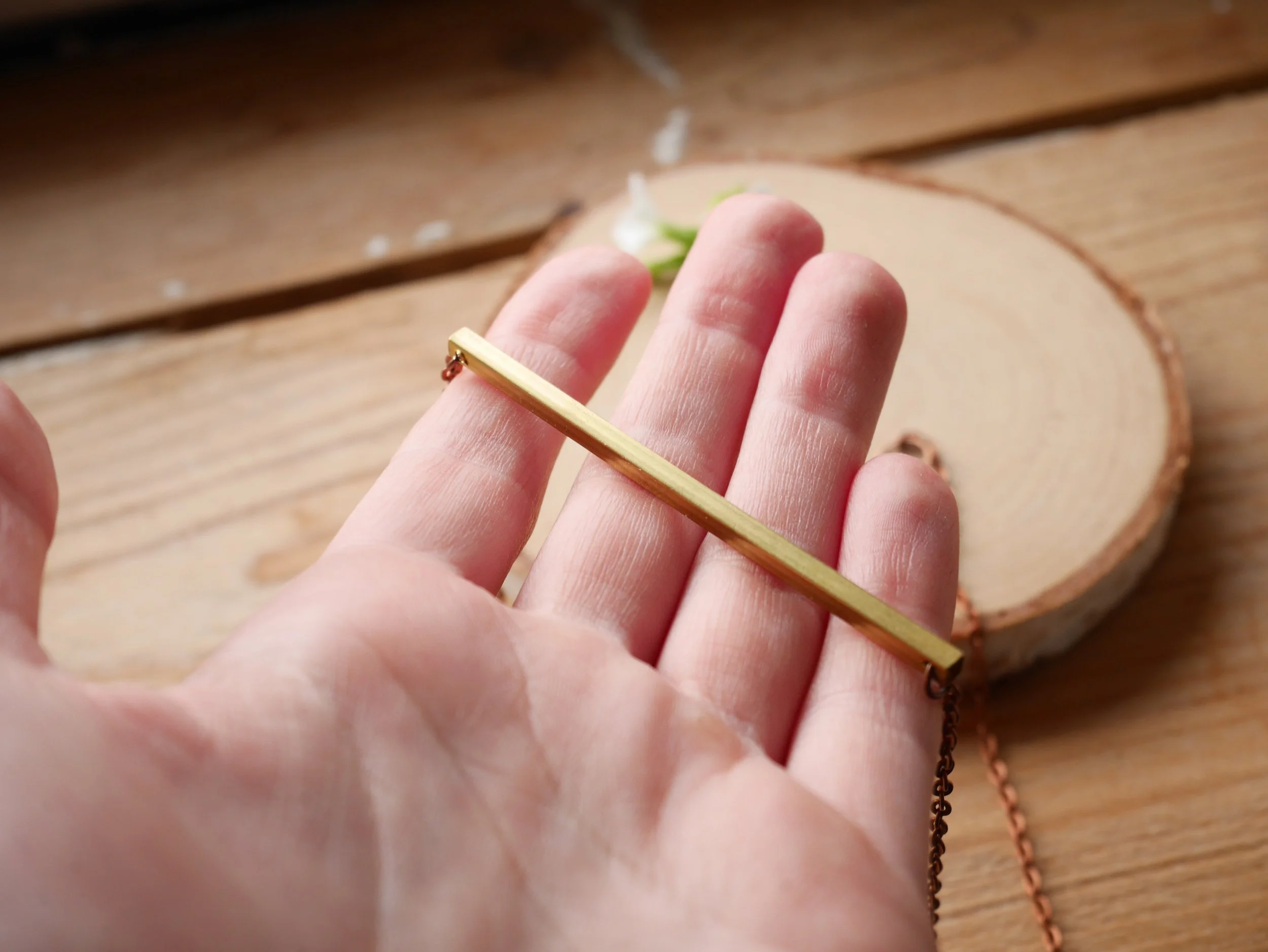 Kupferfarbene Kette mit einem waagerechten goldfarbenen Stab als Verbinder