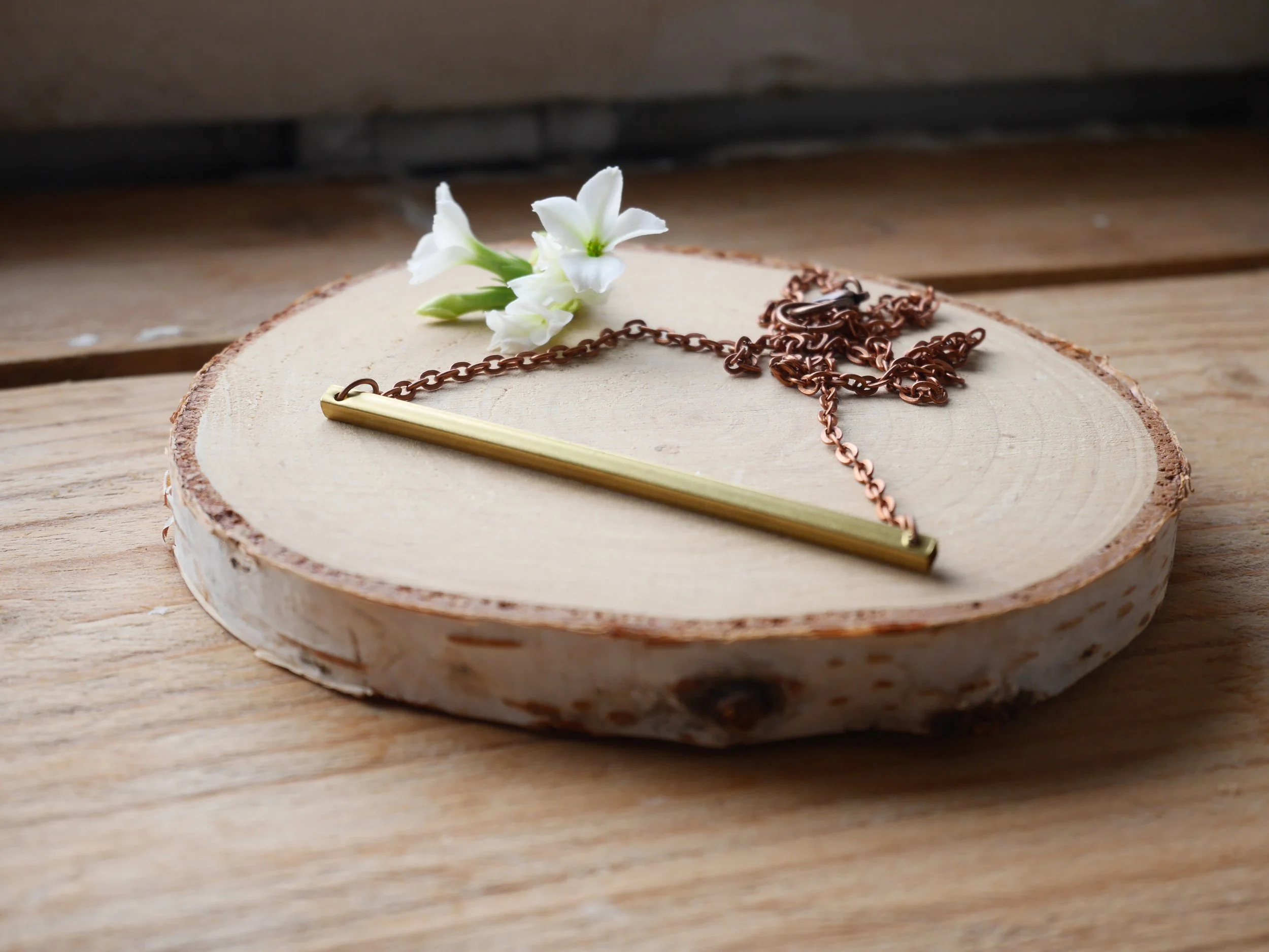 Kupferfarbene Kette mit einem waagerechten goldfarbenen Stab als Verbinder