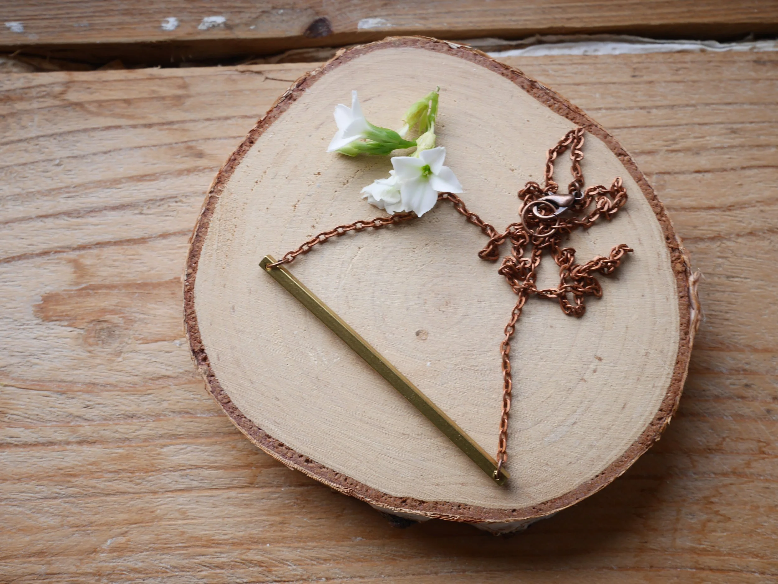 Kupferfarbene Kette mit einem waagerechten goldfarbenen Stab als Verbinder