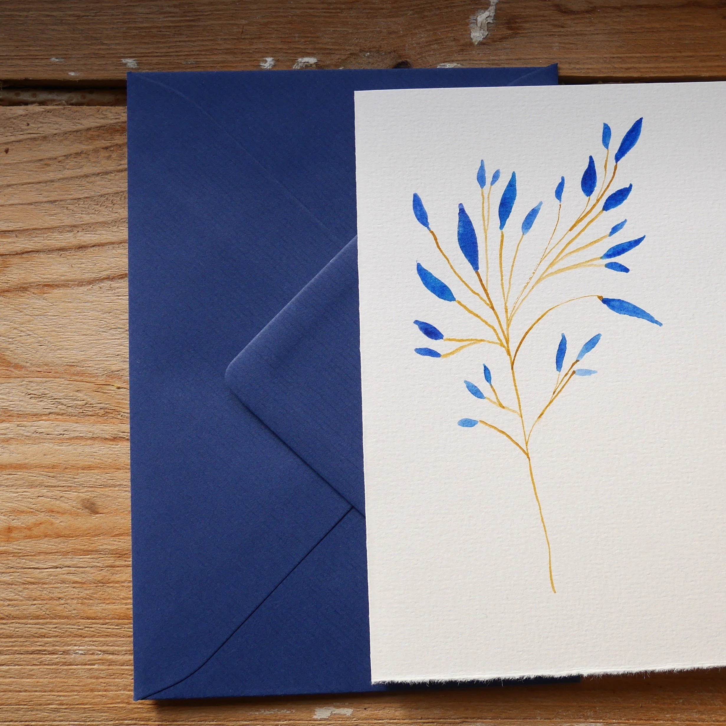 Klappkarte mit gemaltem Zweig mit blauen Blättern und blauem Umschlag