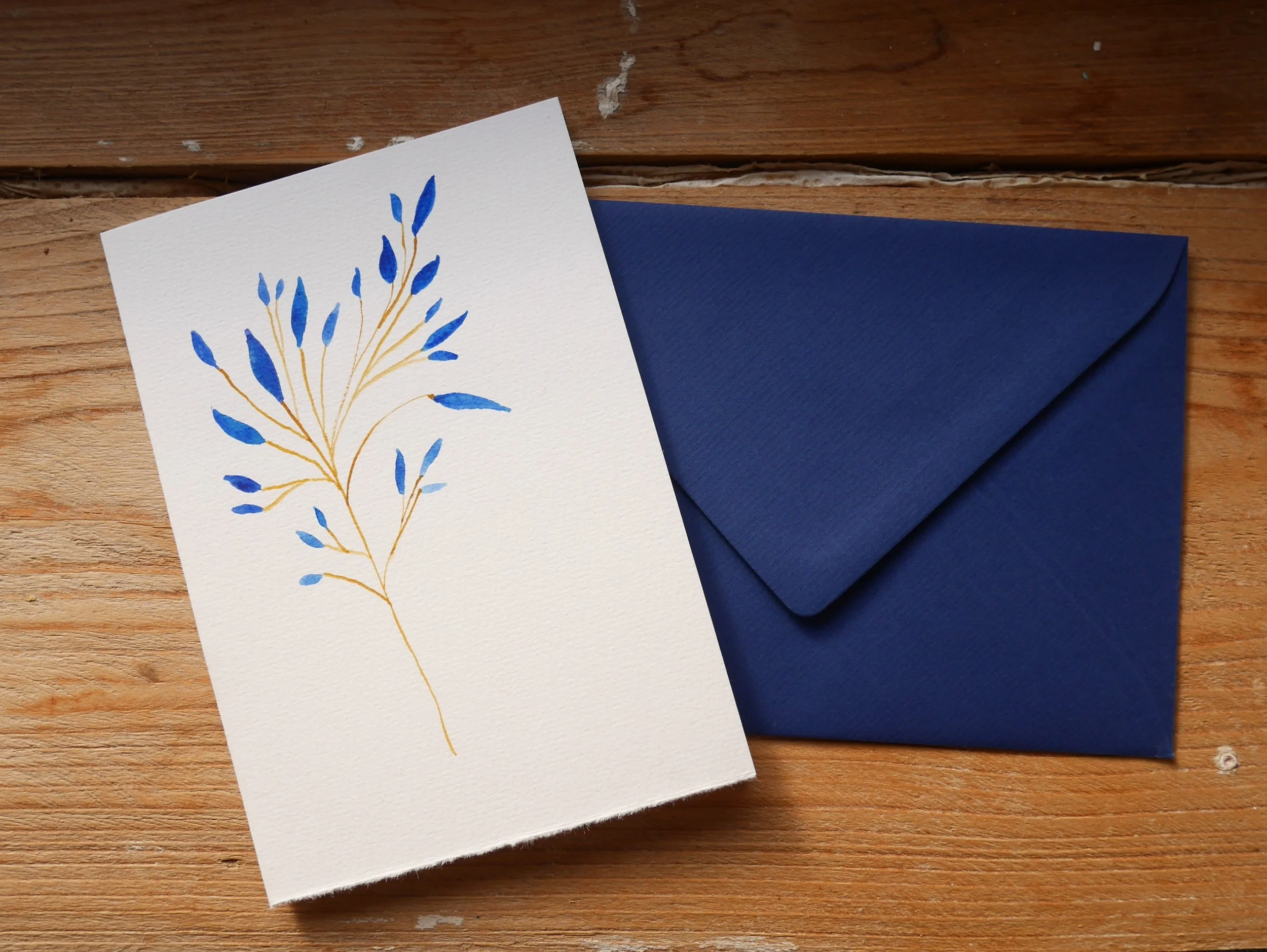 Klappkarte mit gemaltem Zweig mit blauen Blättern und blauem Umschlag
