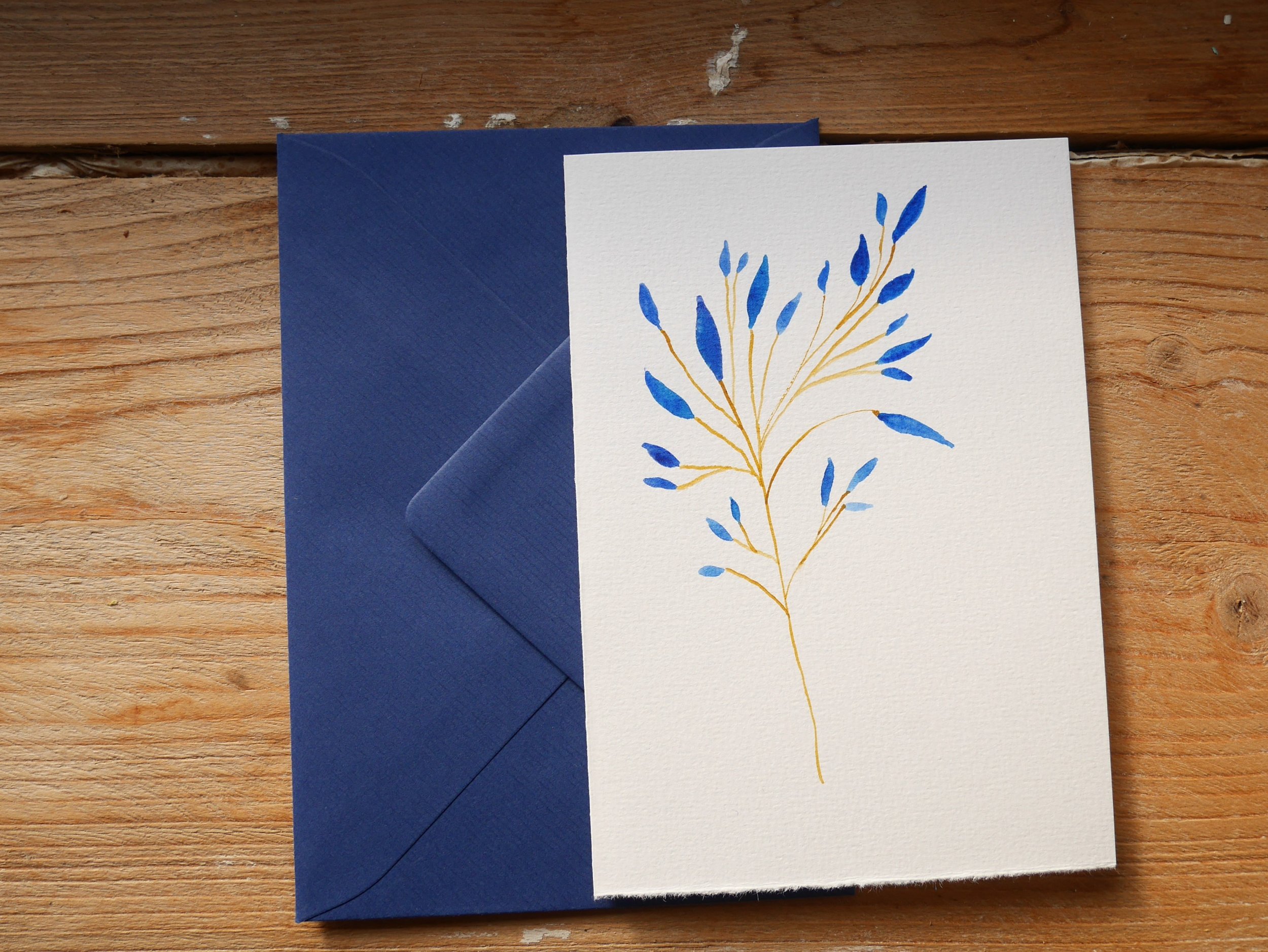 Klappkarte mit gemaltem Zweig mit blauen Blättern und blauem Umschlag