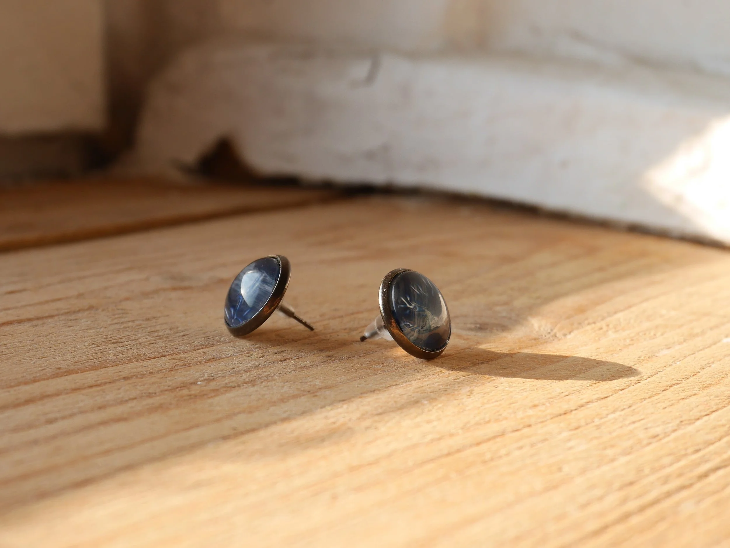 ein Paar runde Ohrstecker mit dunkelblauen Glassteinen