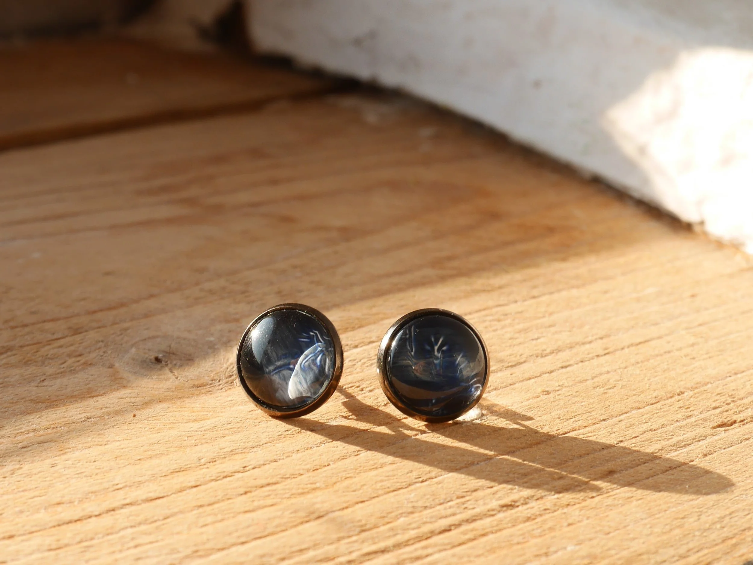 ein Paar runde Ohrstecker mit dunkelblauen Glassteinen