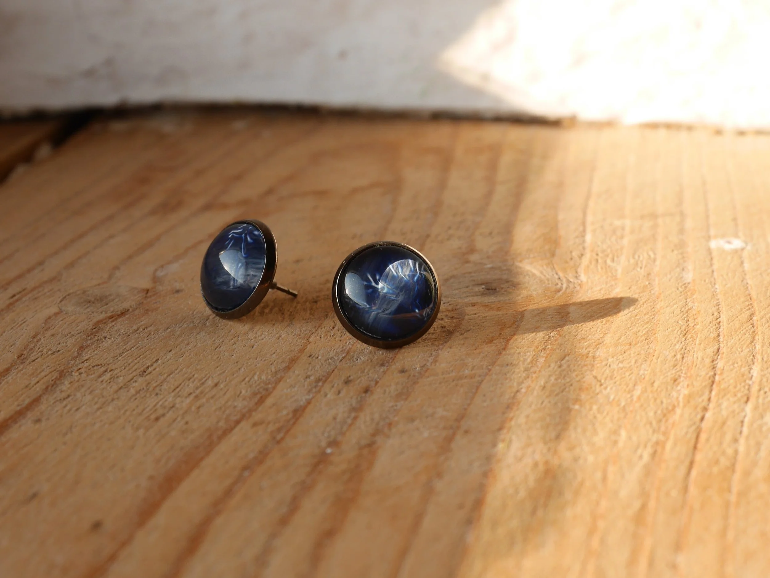 ein Paar runde Ohrstecker mit dunkelblauen Glassteinen