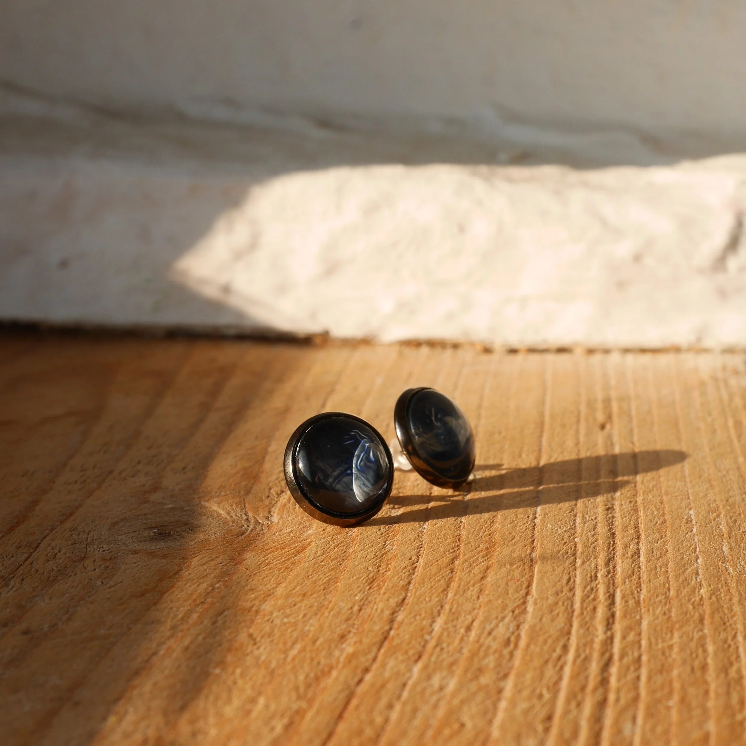 ein Paar runde Ohrstecker mit dunkelblauen Glassteinen