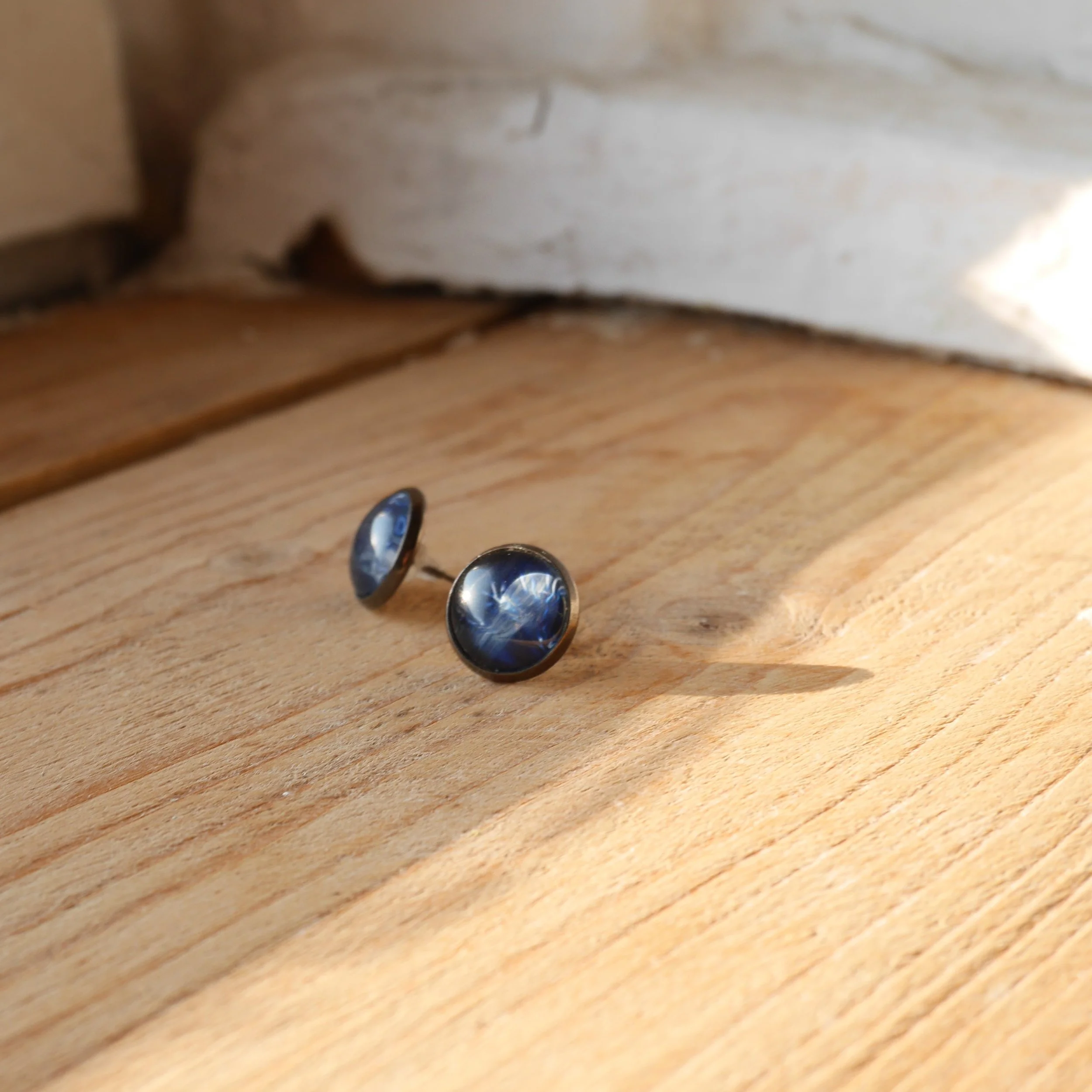 ein Paar runde Ohrstecker mit dunkelblauen Glassteinen