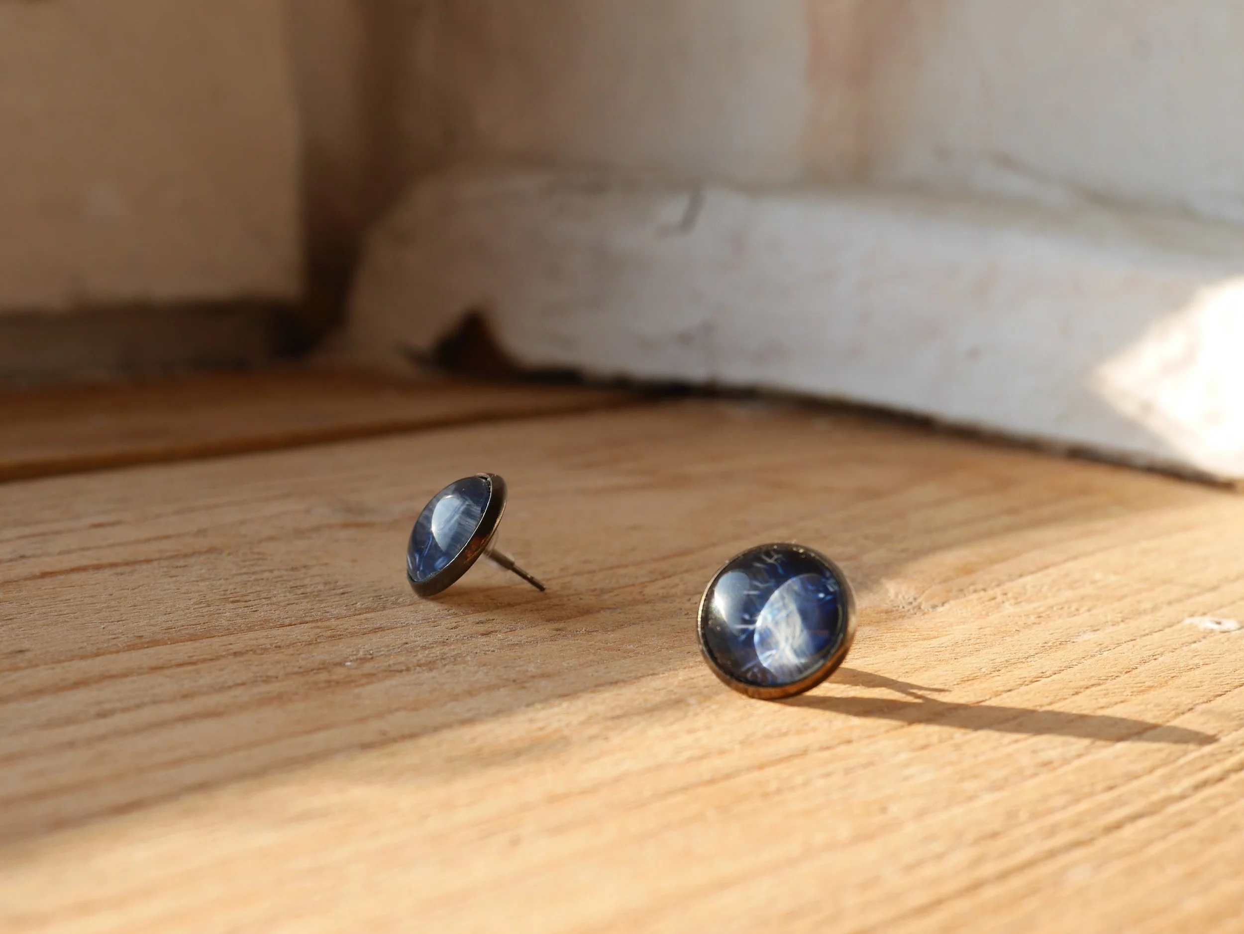 ein Paar runde Ohrstecker mit dunkelblauen Glassteinen