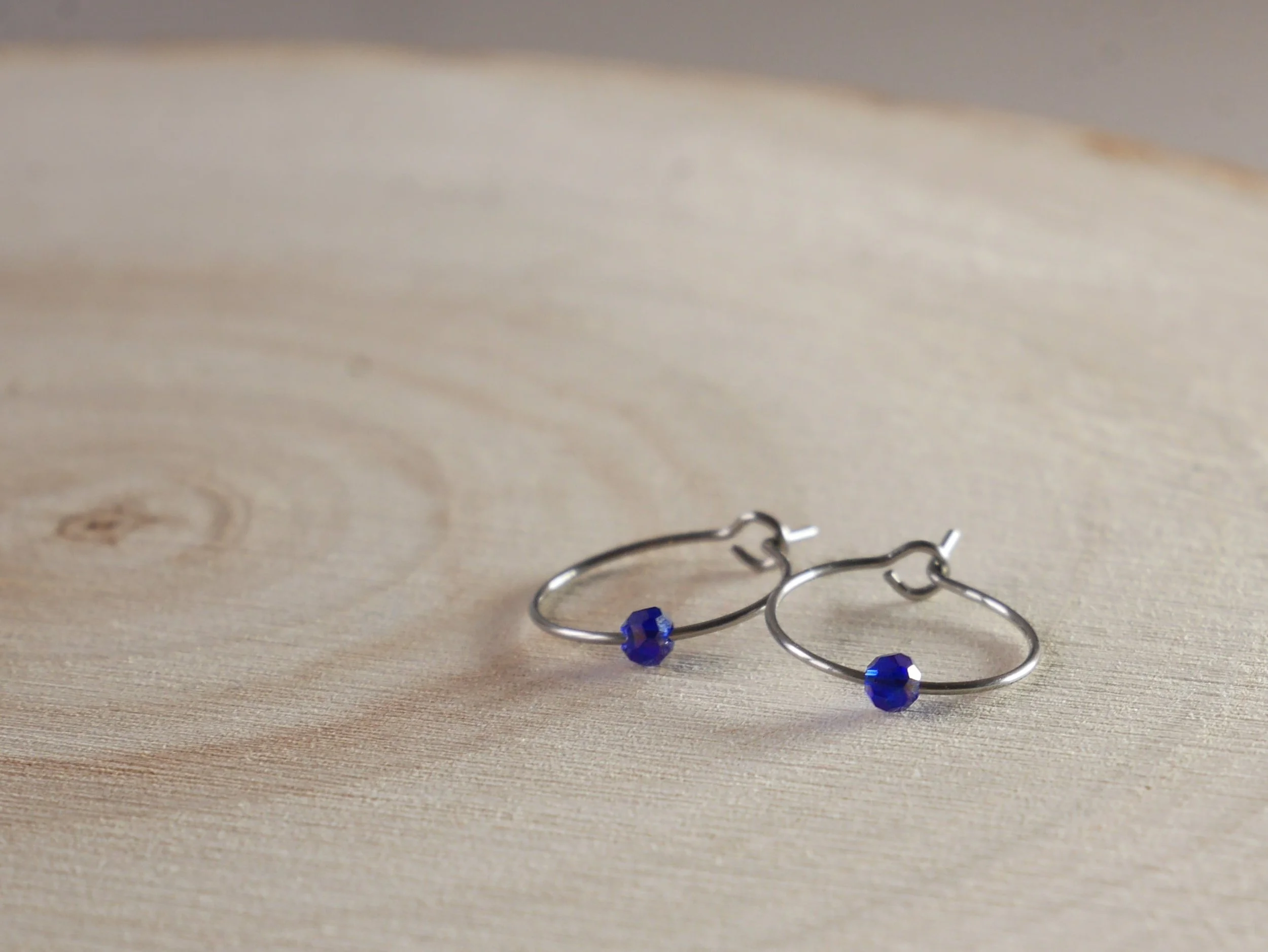 Kleine silberfarbene Creolen mit jeweils einer winzigen blauen Acrylperle