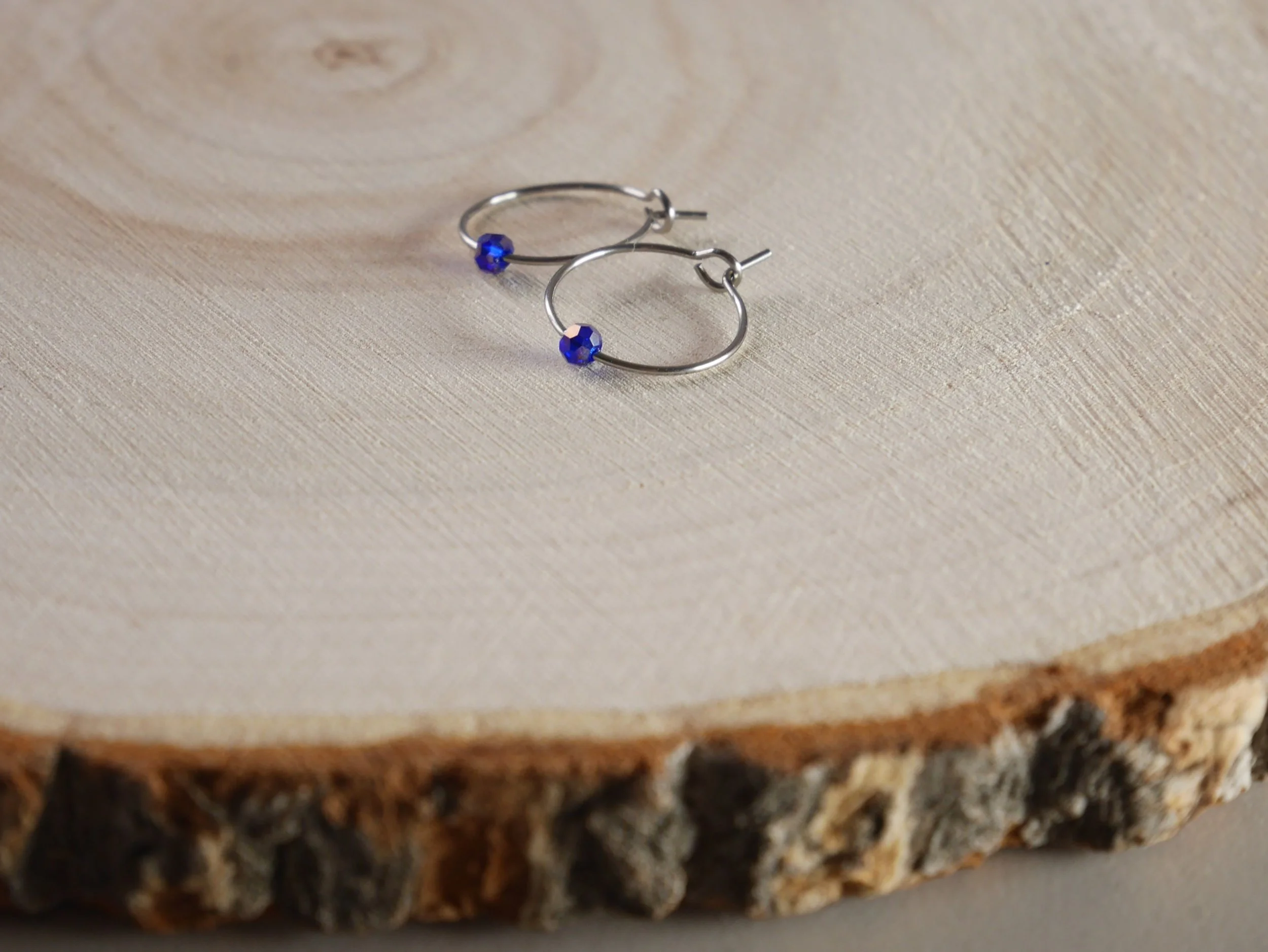 Kleine silberfarbene Creolen mit jeweils einer winzigen blauen Acrylperle