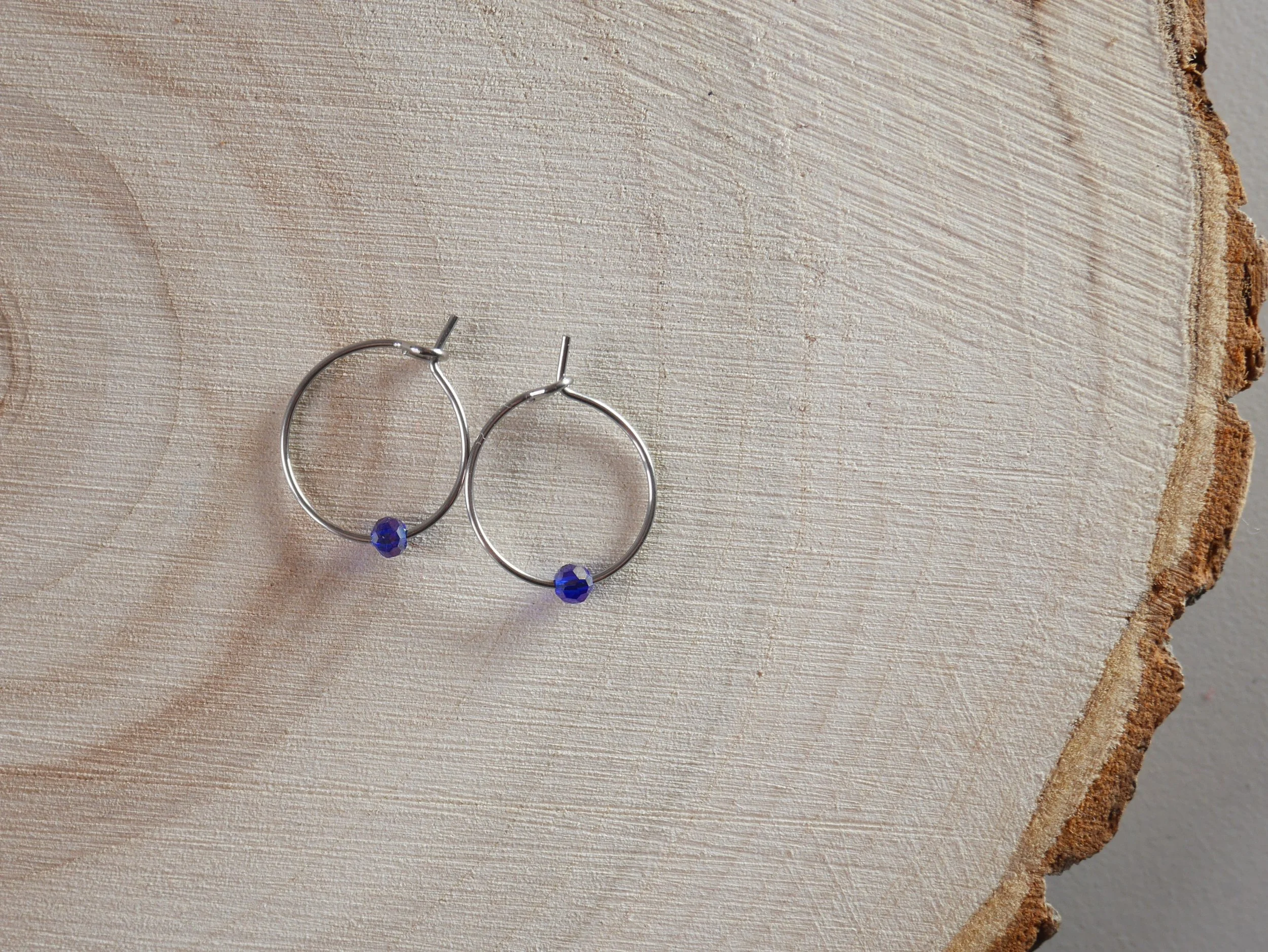 Kleine silberfarbene Creolen mit jeweils einer winzigen blauen Acrylperle