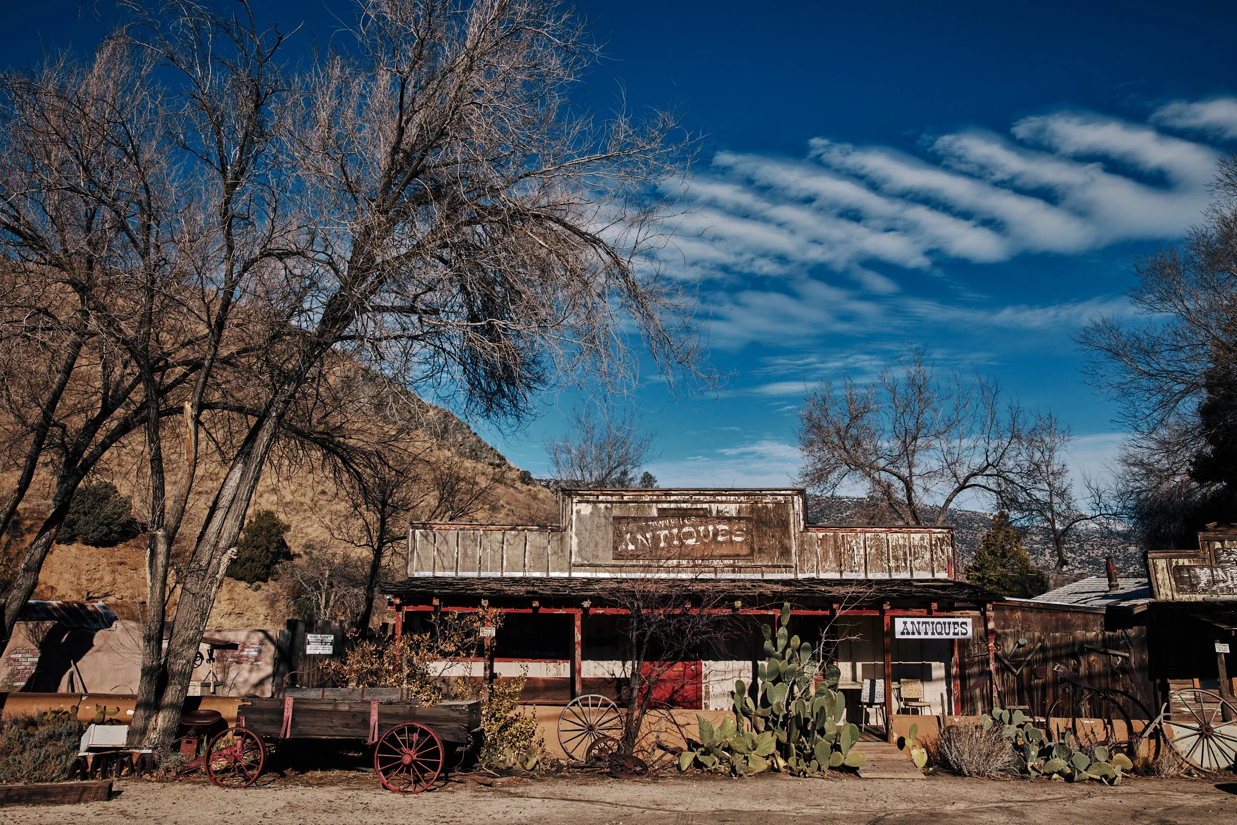 Old Western-style antique shop with wooden wagon and desert landscape.
