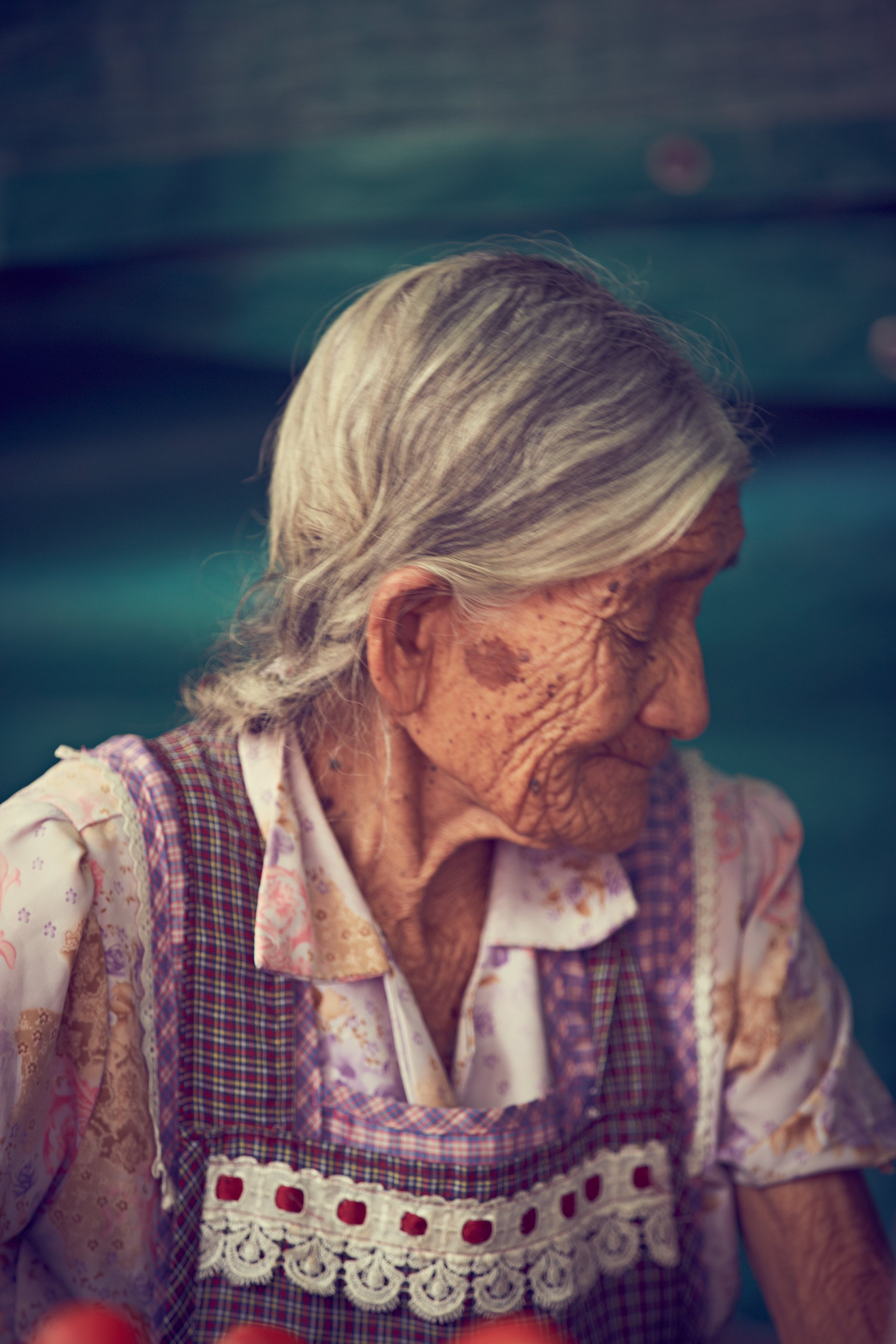 Elderly woman with gray hair, wearing patterned dress and apron