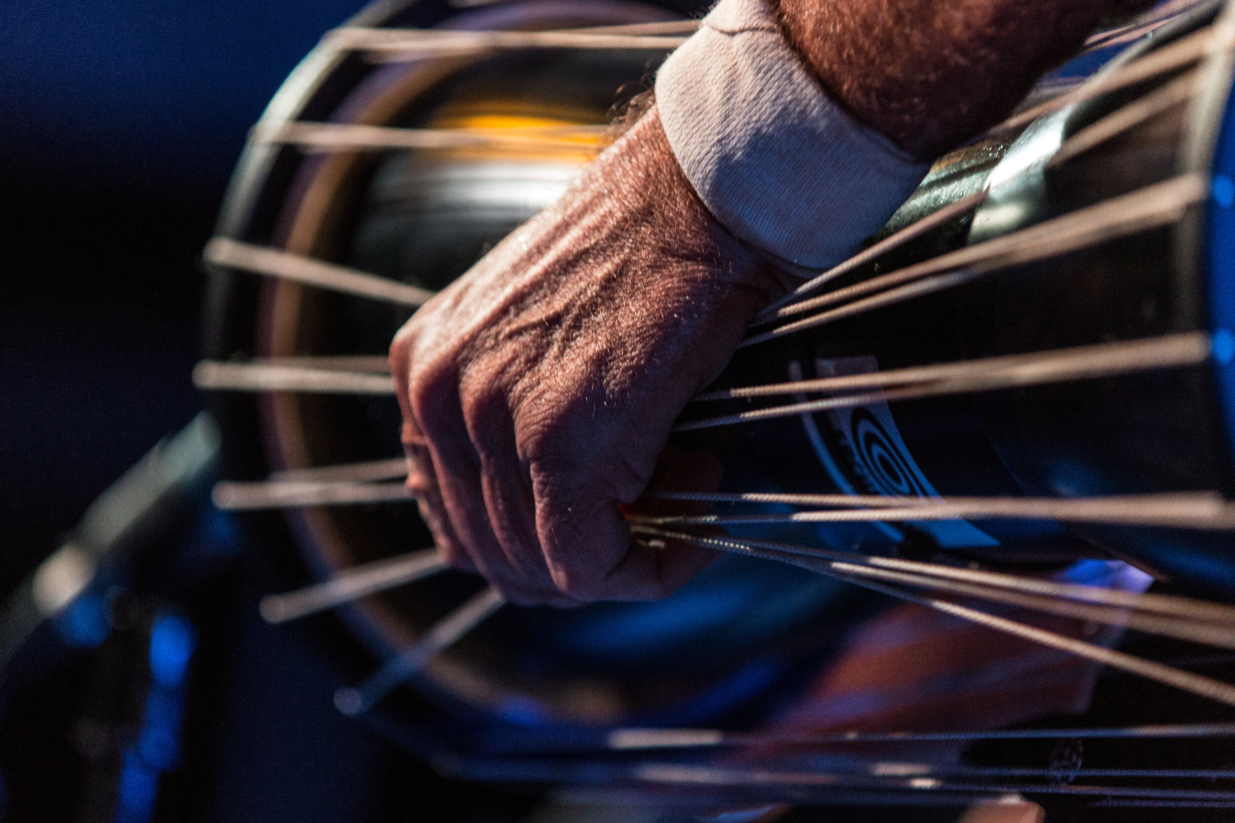 Close-up of a hand playing a percussion instrument with tension cables.