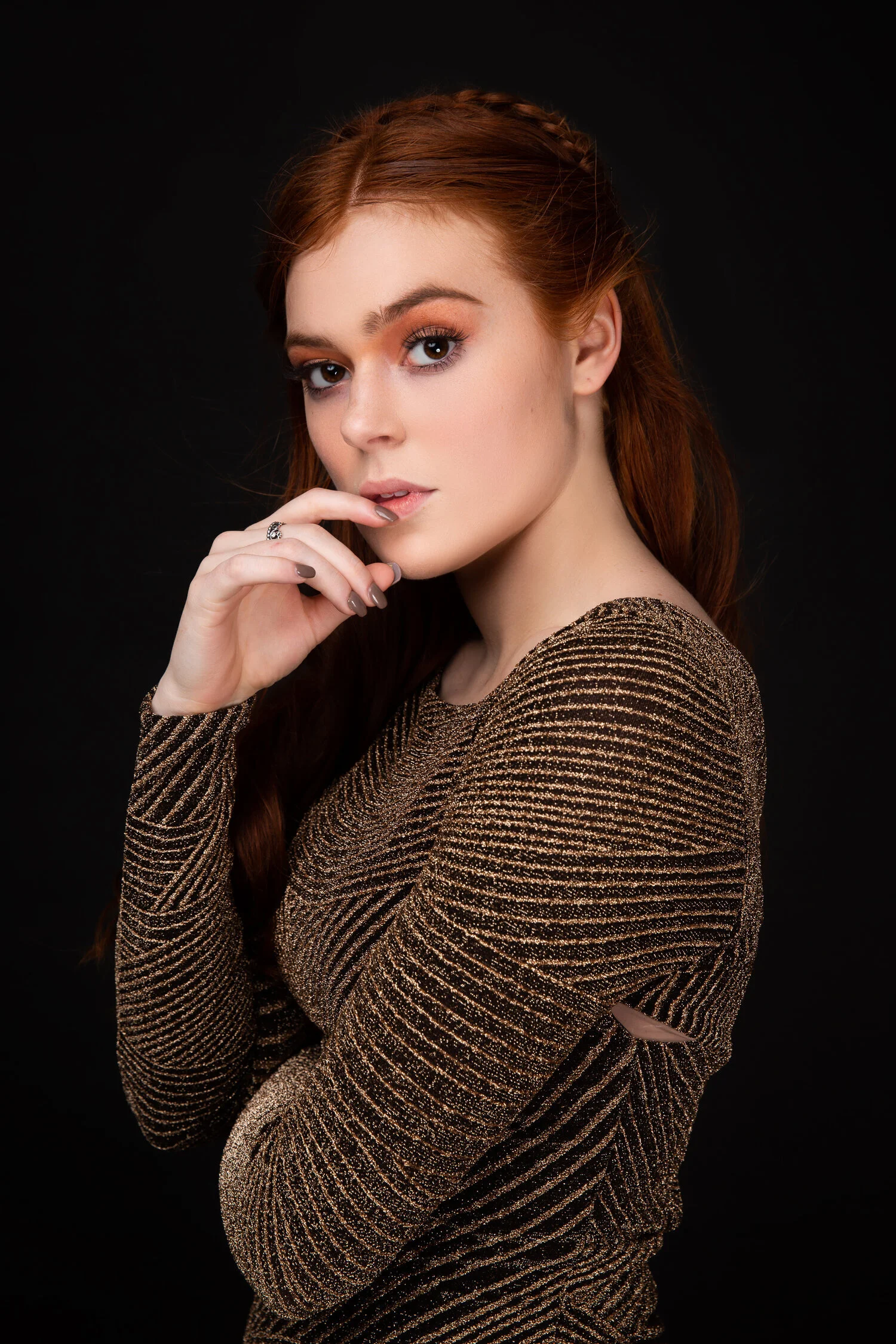 Woman with red hair in a sparkly, striped dress posing against a black background