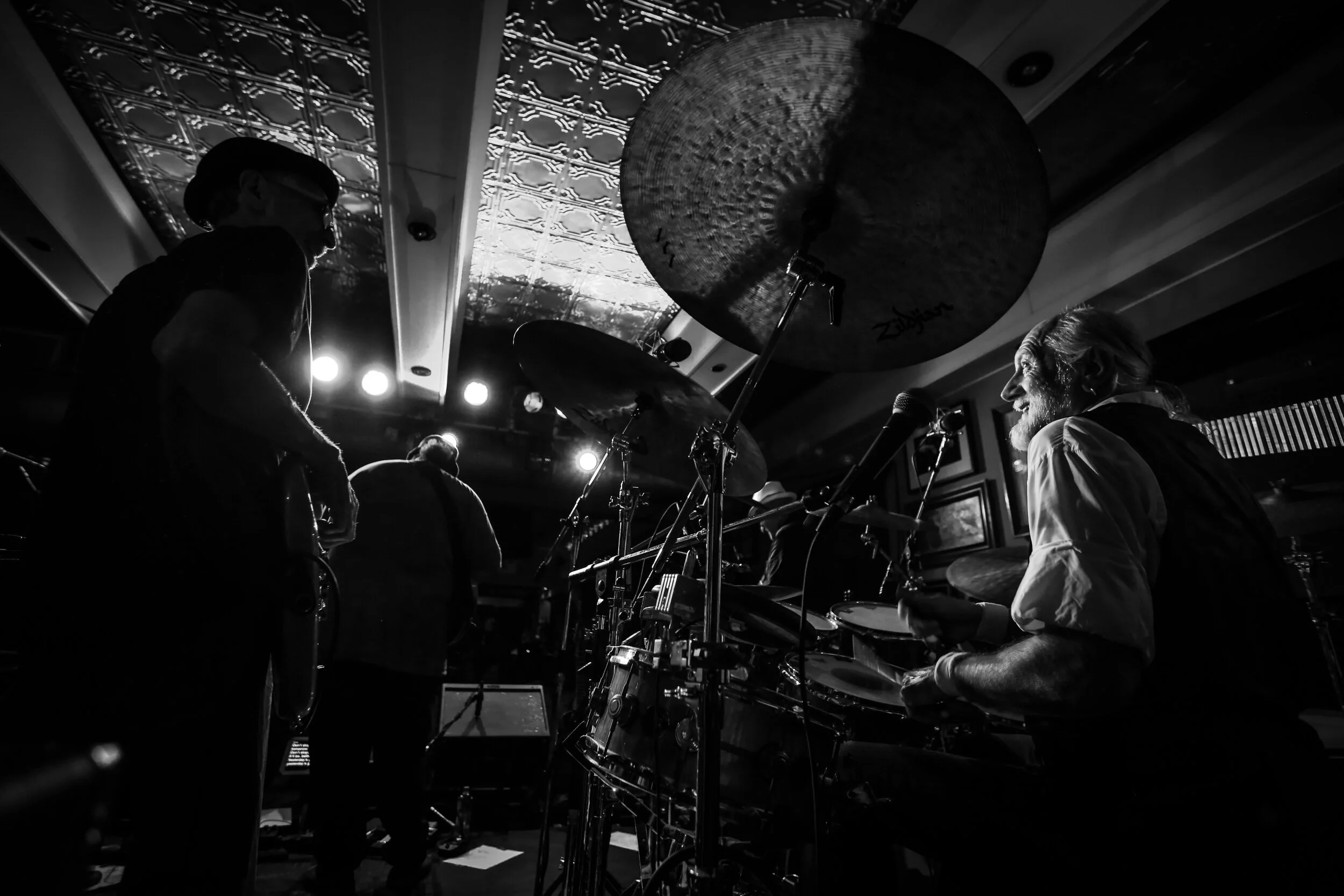 Black and white photo of a live band performance with drummer and musicians.