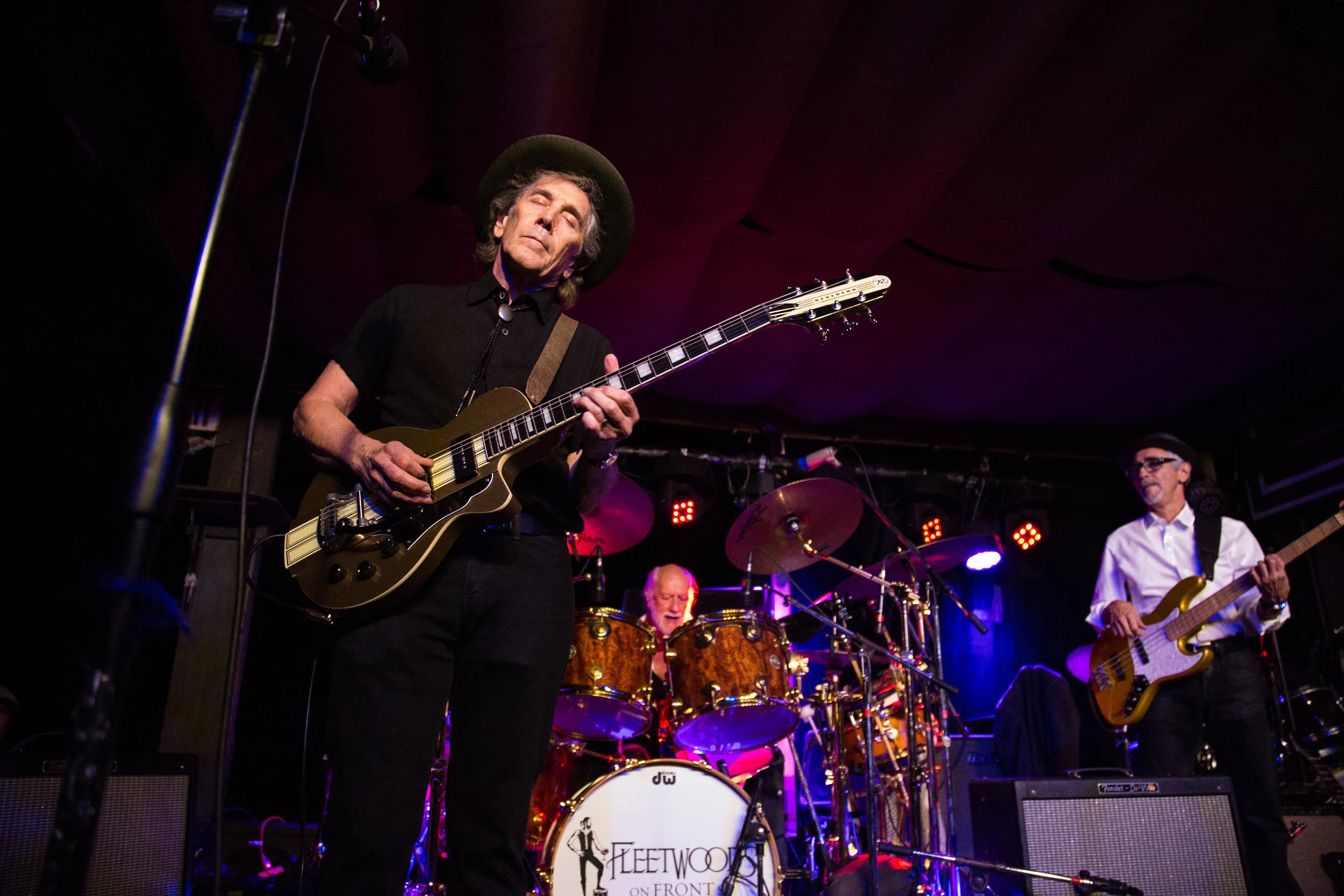 Live band performance with guitarist, drummer, and bassist on stage