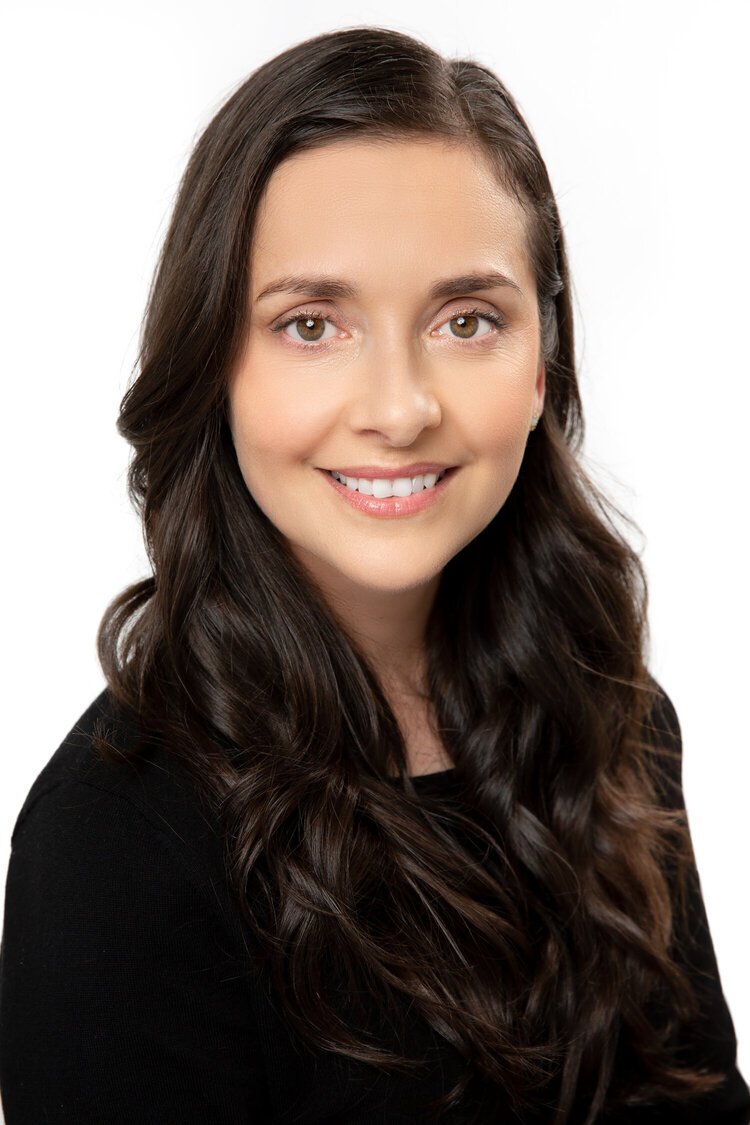 Portrait of a woman with long dark hair smiling against a white background.
