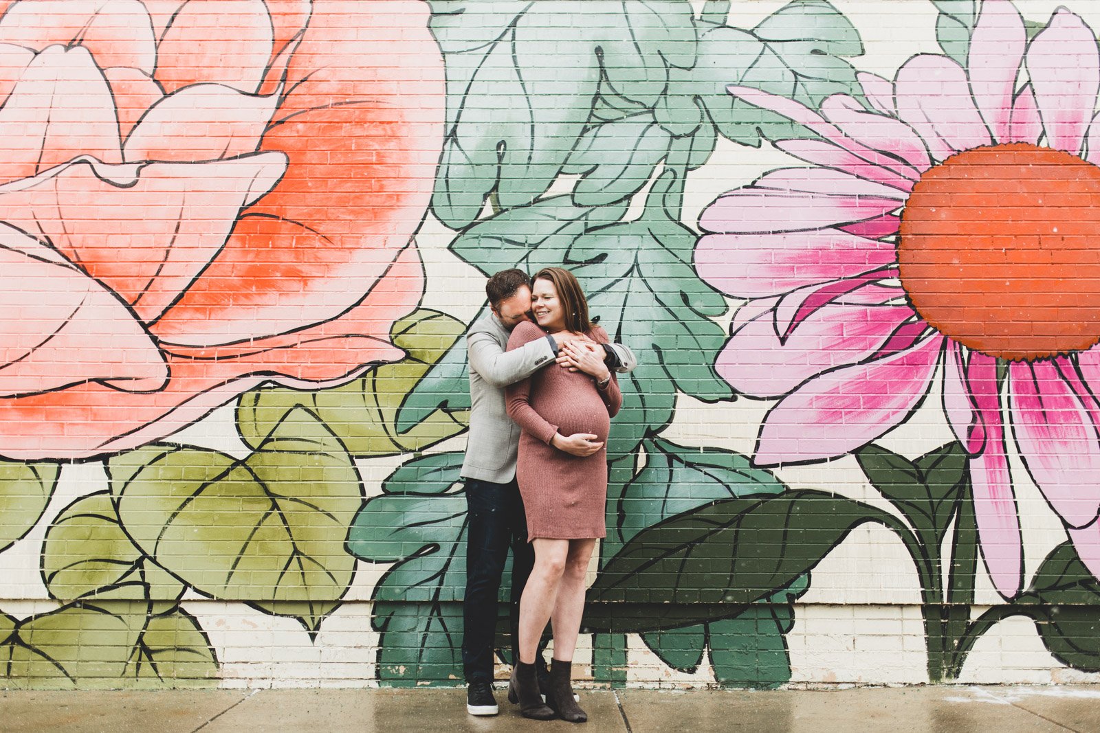 expecting-couple-hugging-flower-mural.jpg