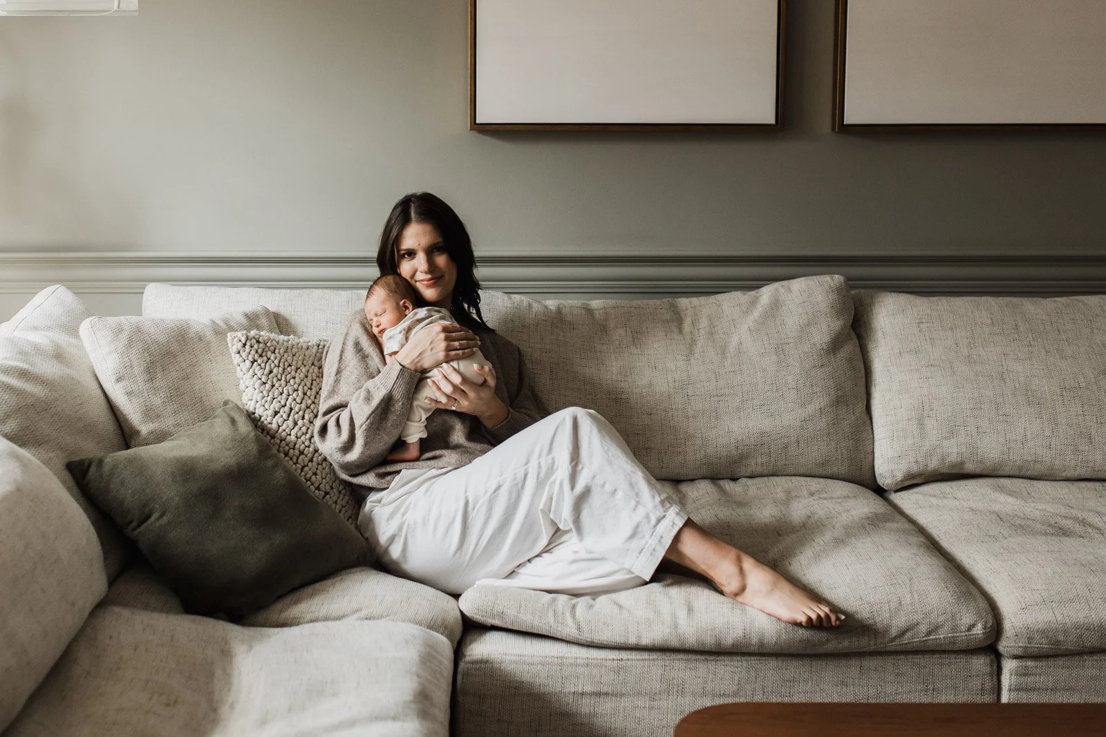 mother holding newborn baby on couch