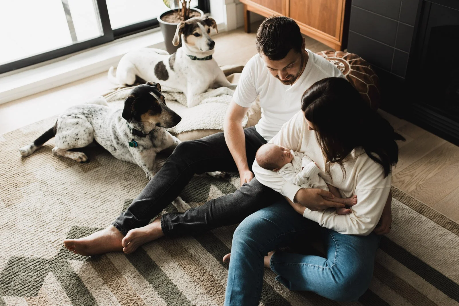 mom and dad with new baby and dogs on floor 