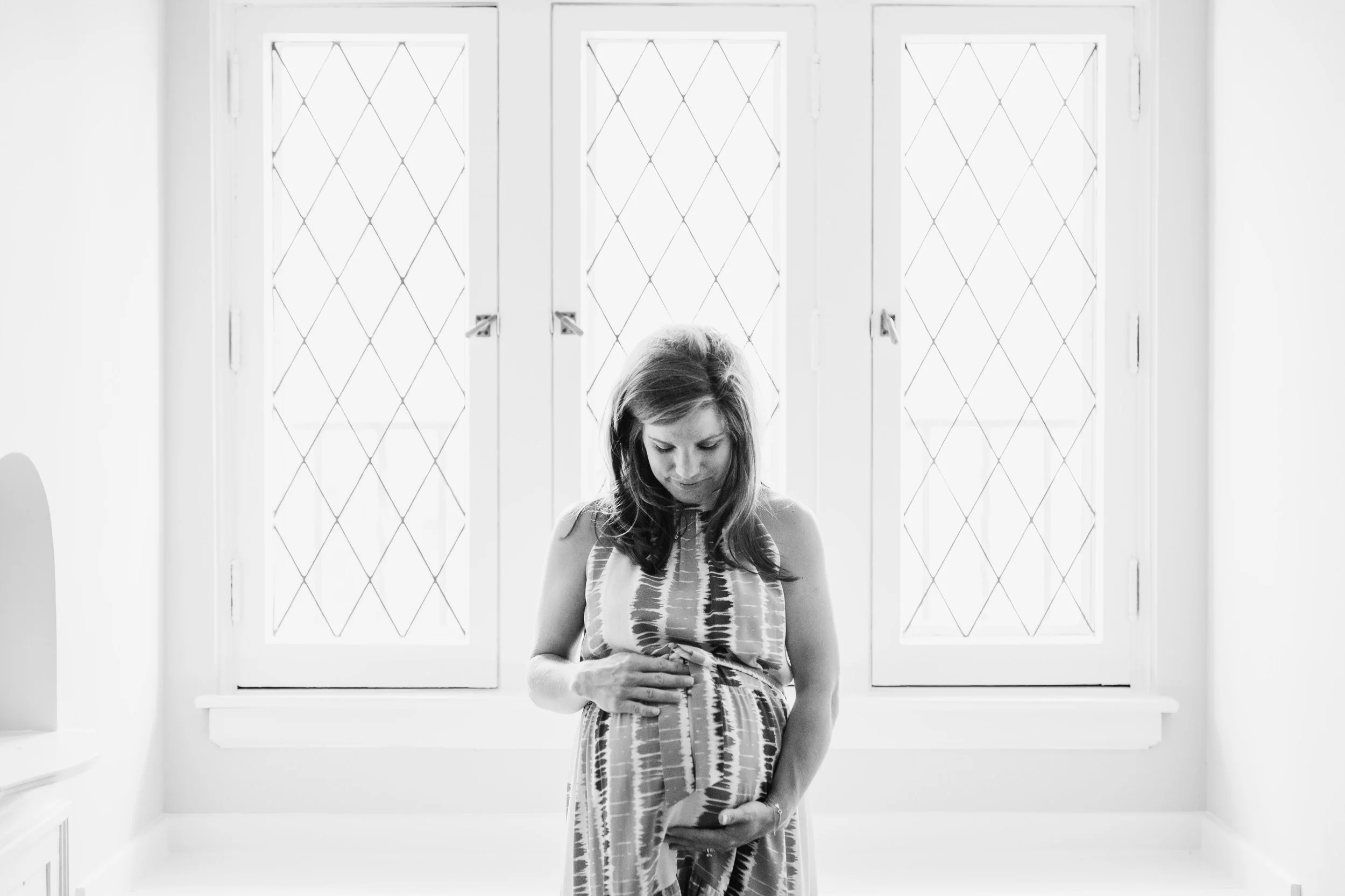 black and white pregnant woman looking down at belly